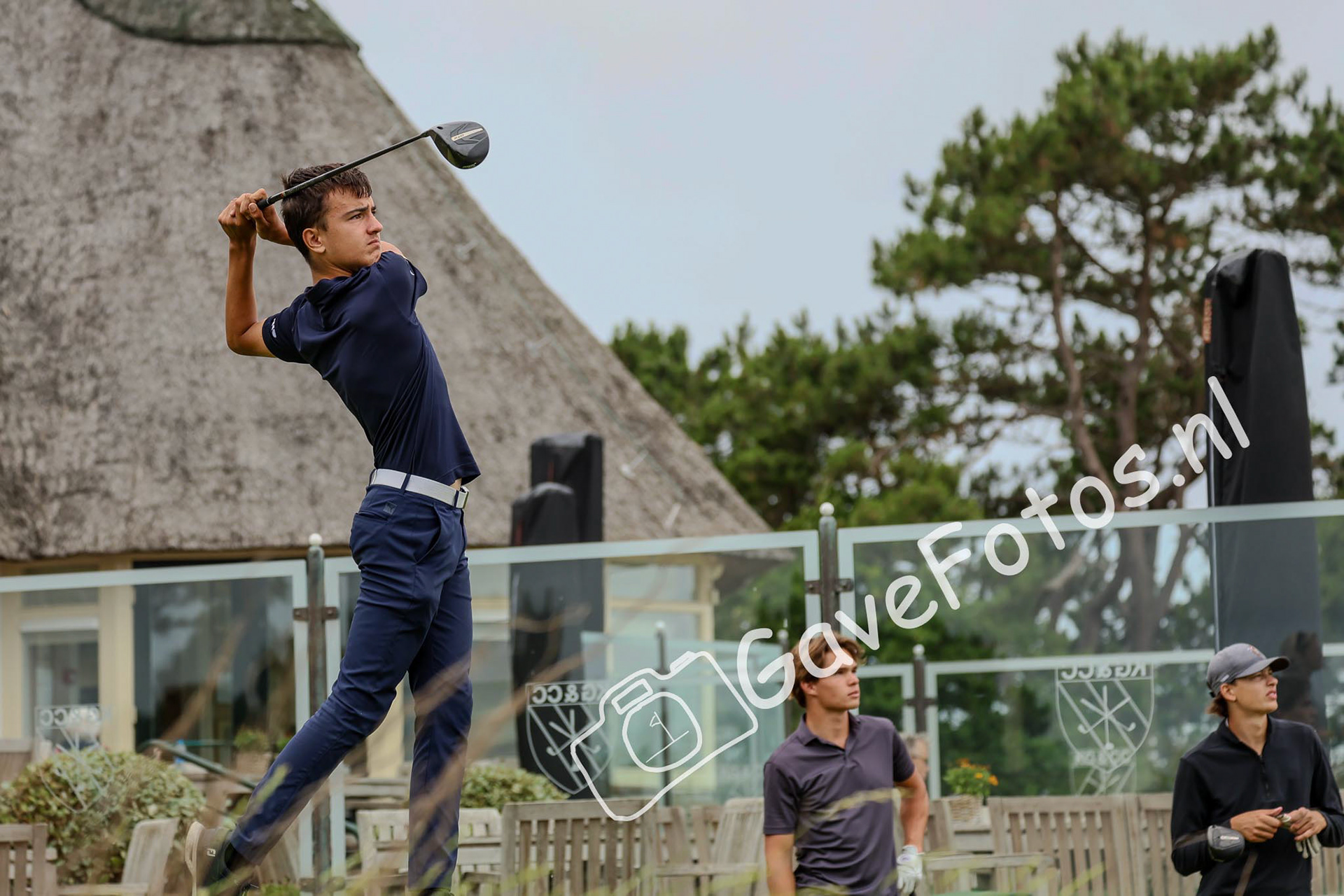 Jesse van Doorn slaat op op hole 10, naast het clubhuis van de Kennemer Golf en Country Club