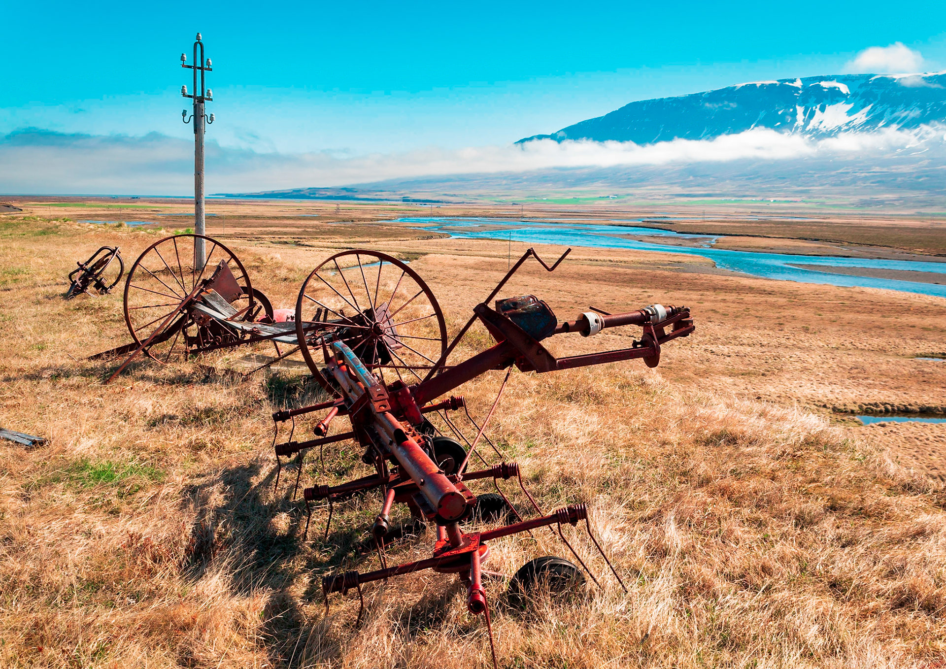 Old farm machinery stands witness over Smjörfjöll mountain range.