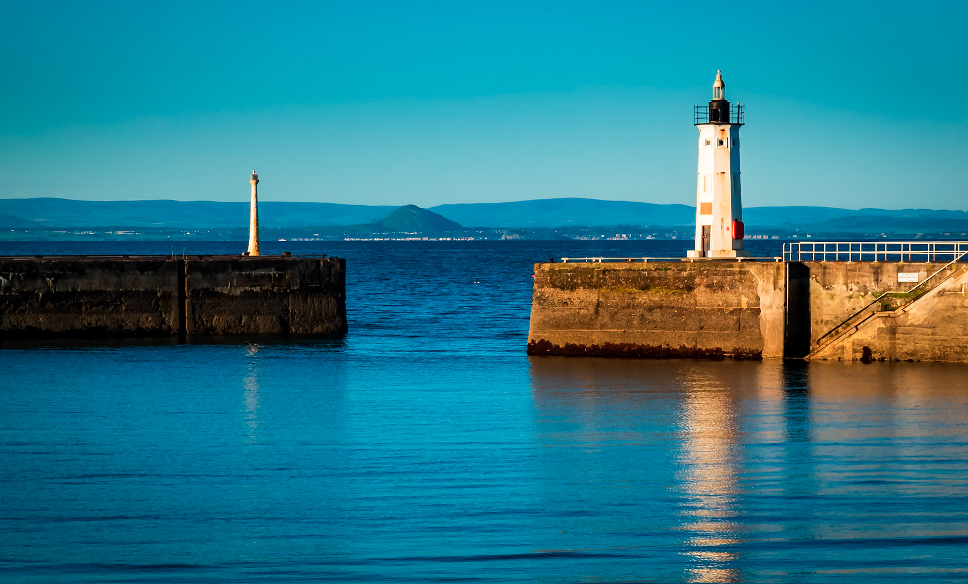 Looking through a gap through Anstruther Harbour's breakwaters across the River Forth's Estuary to North Berwick and its conical hill.
