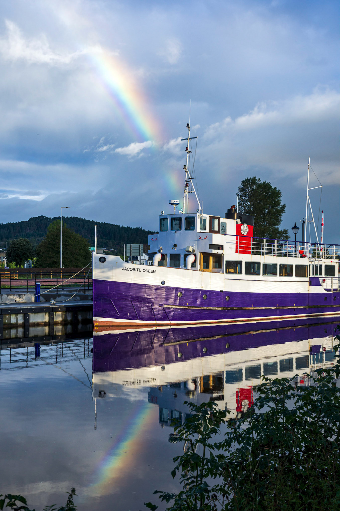 A rainbow pierces the Jacobite Queen tour boat on the Caledonian Canal.