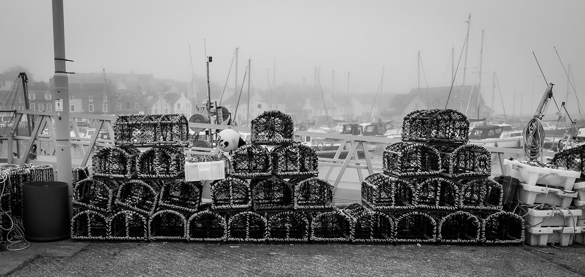 After day that has been foggy all the way through the harbour's boats and fishing pots sits waiting for a better day tomorrow.