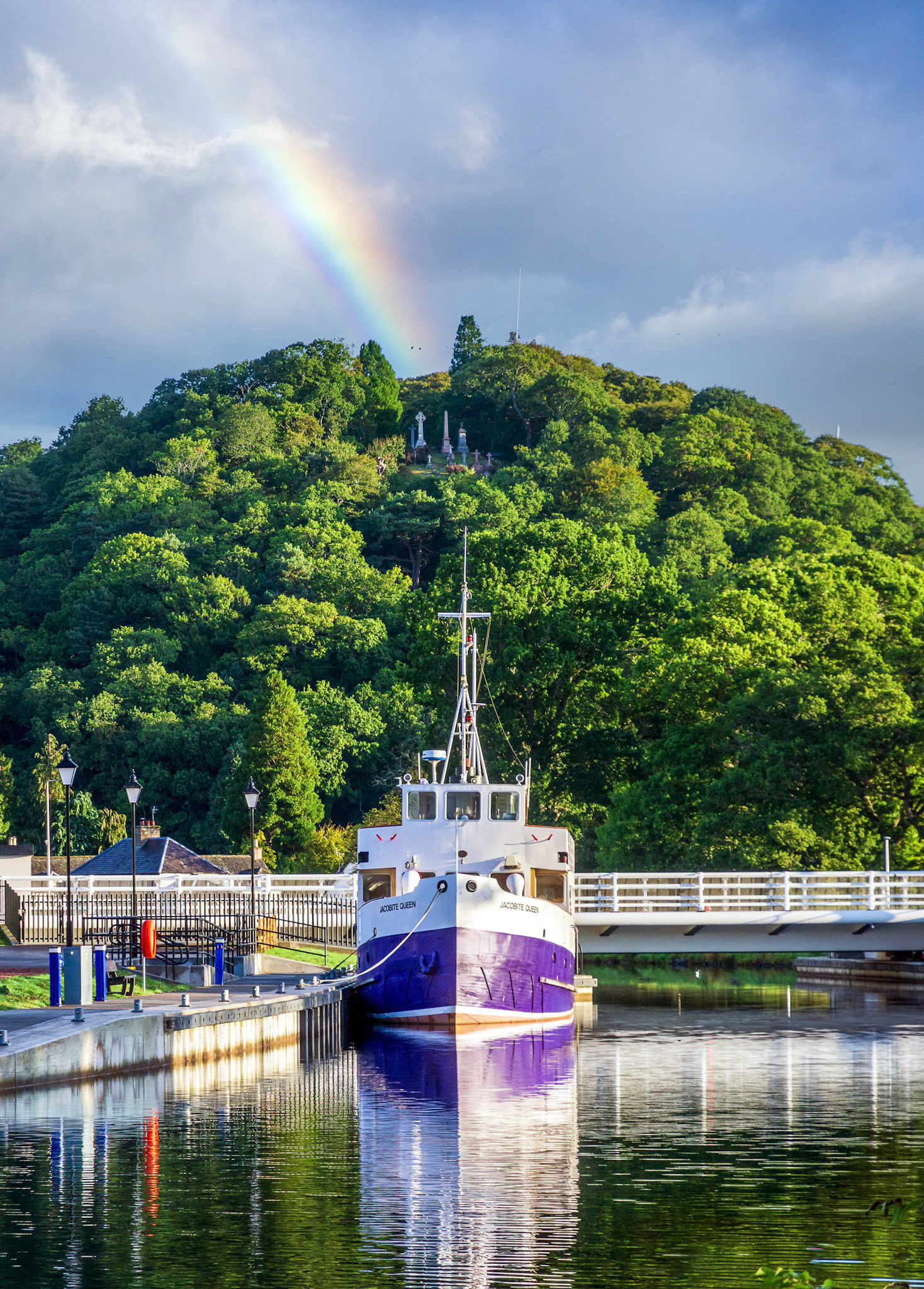 The graves of Tomnahurich Cemetery look down on the Jacobite Queen tour boat on the Caledonian Canal.