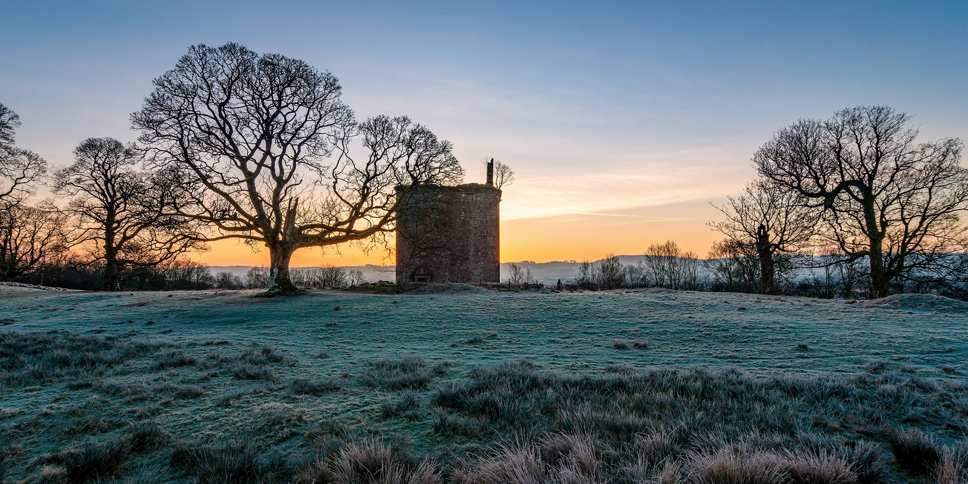 On frosty cold morning a small castle bathes in the early warming golden rays of the sun.