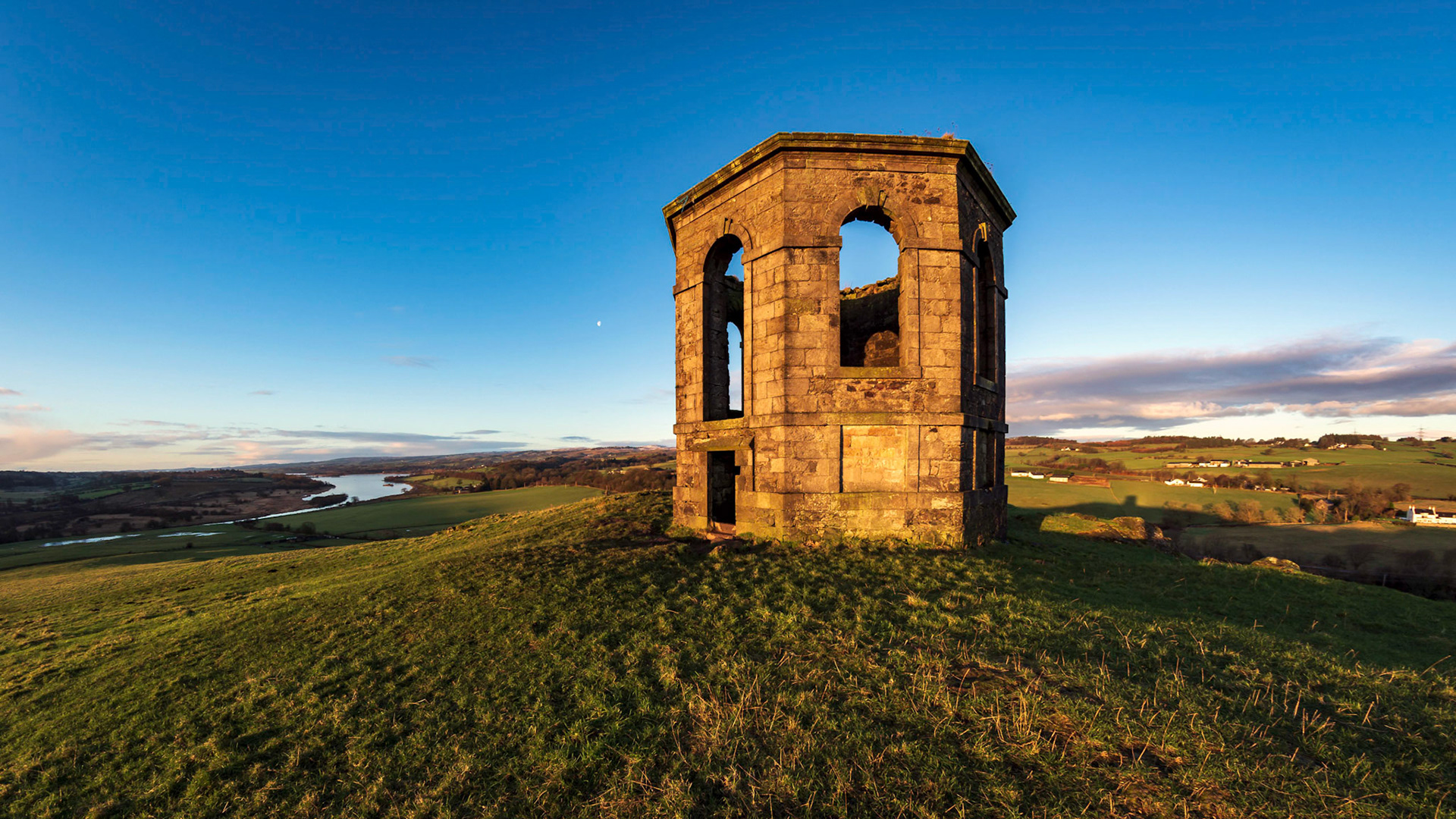 The early morning light strikes the side of Kenmure Hill Temple while looking down on Cast Semple Loch and the villgae of Lochwinnoch.