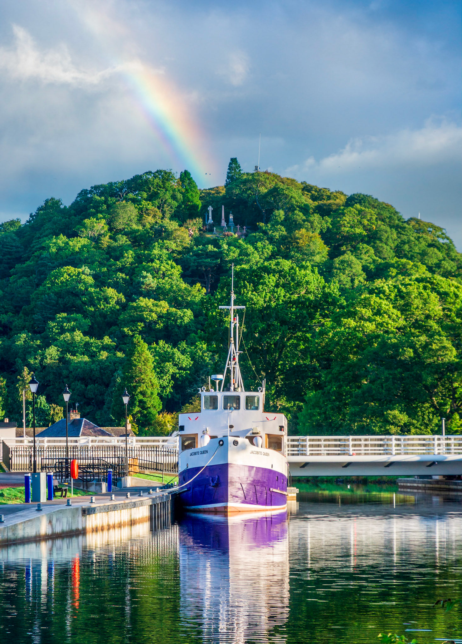 The graves of Tomnahurich Cemetery look down on the Jacobite Queen tour boat on the Caledonian Canal.