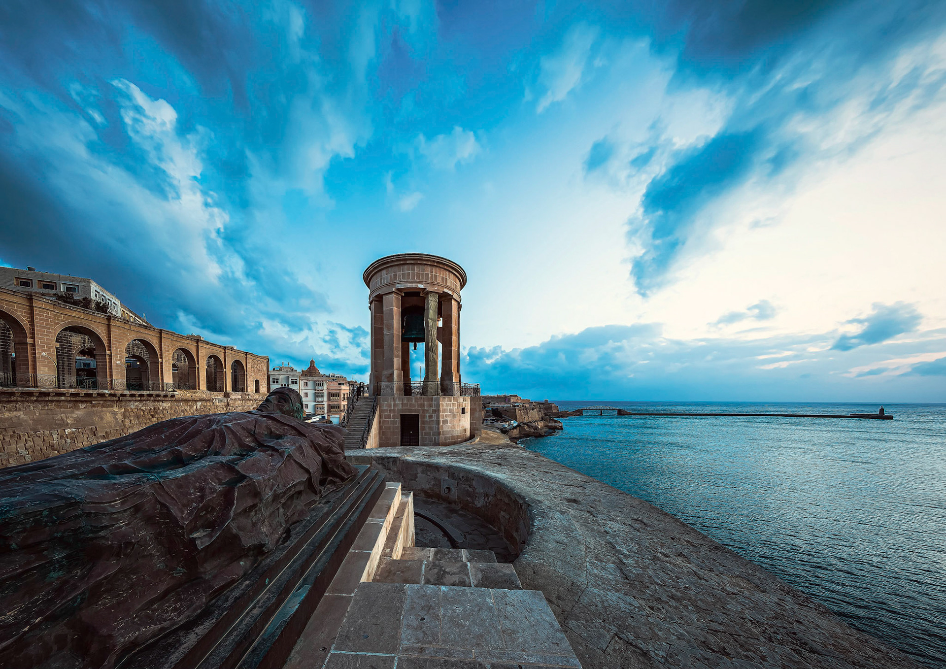 The memorial was constructed to commemorate those that died in Malta during the second world war. The bronze statue on a catafalque represents the unknown soldier about to be comitted to the sea.