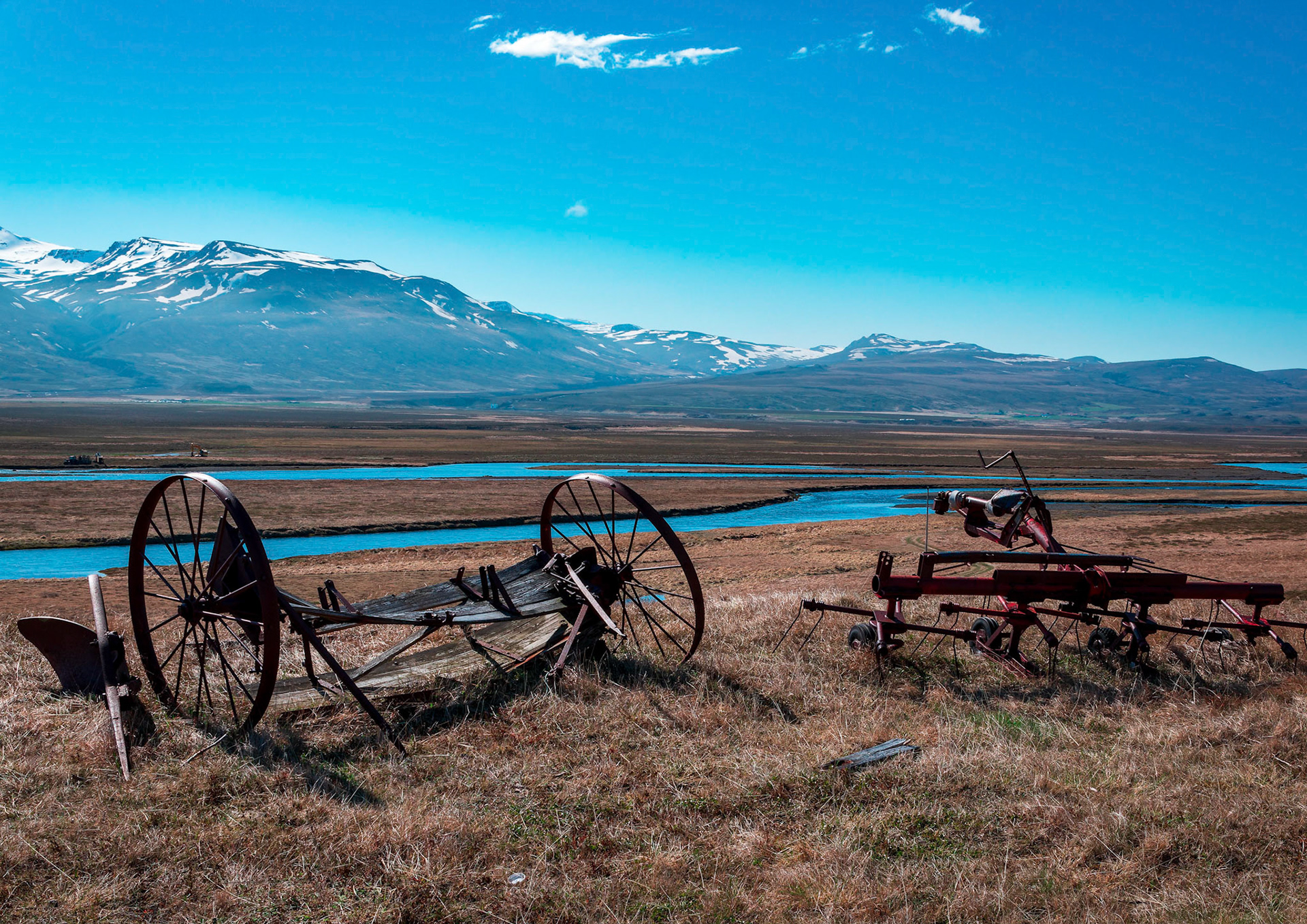 Old farm machinery stands witness over Smjörfjöll mountain range.