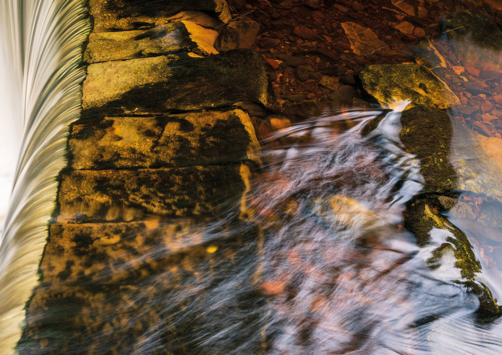 The River Calder (Renfrewshire) flows slowly towards the edge of the weir and then falls rapidly at the lip.