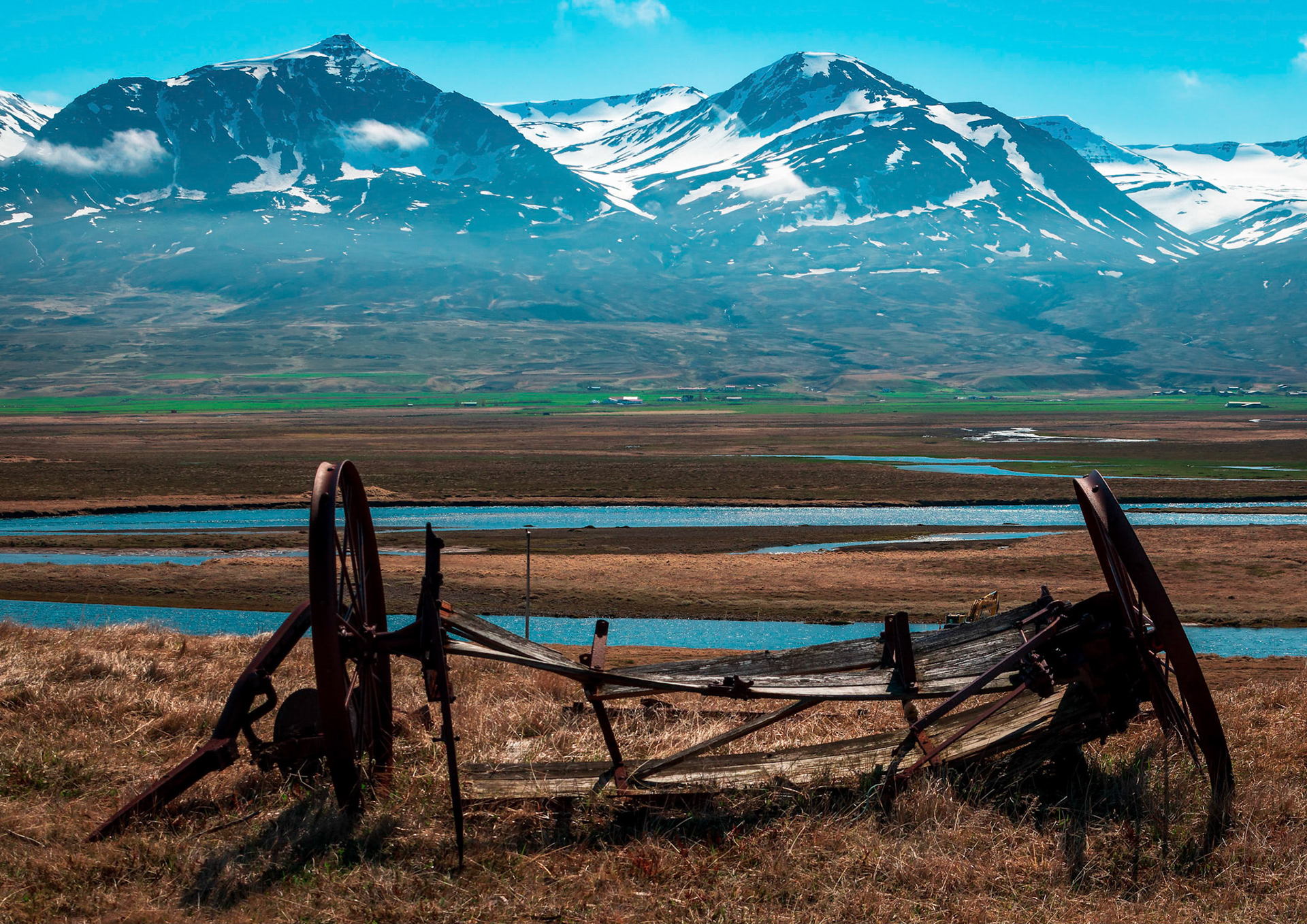 Old farm machinery stands witness over Smjörfjöll mountain range.