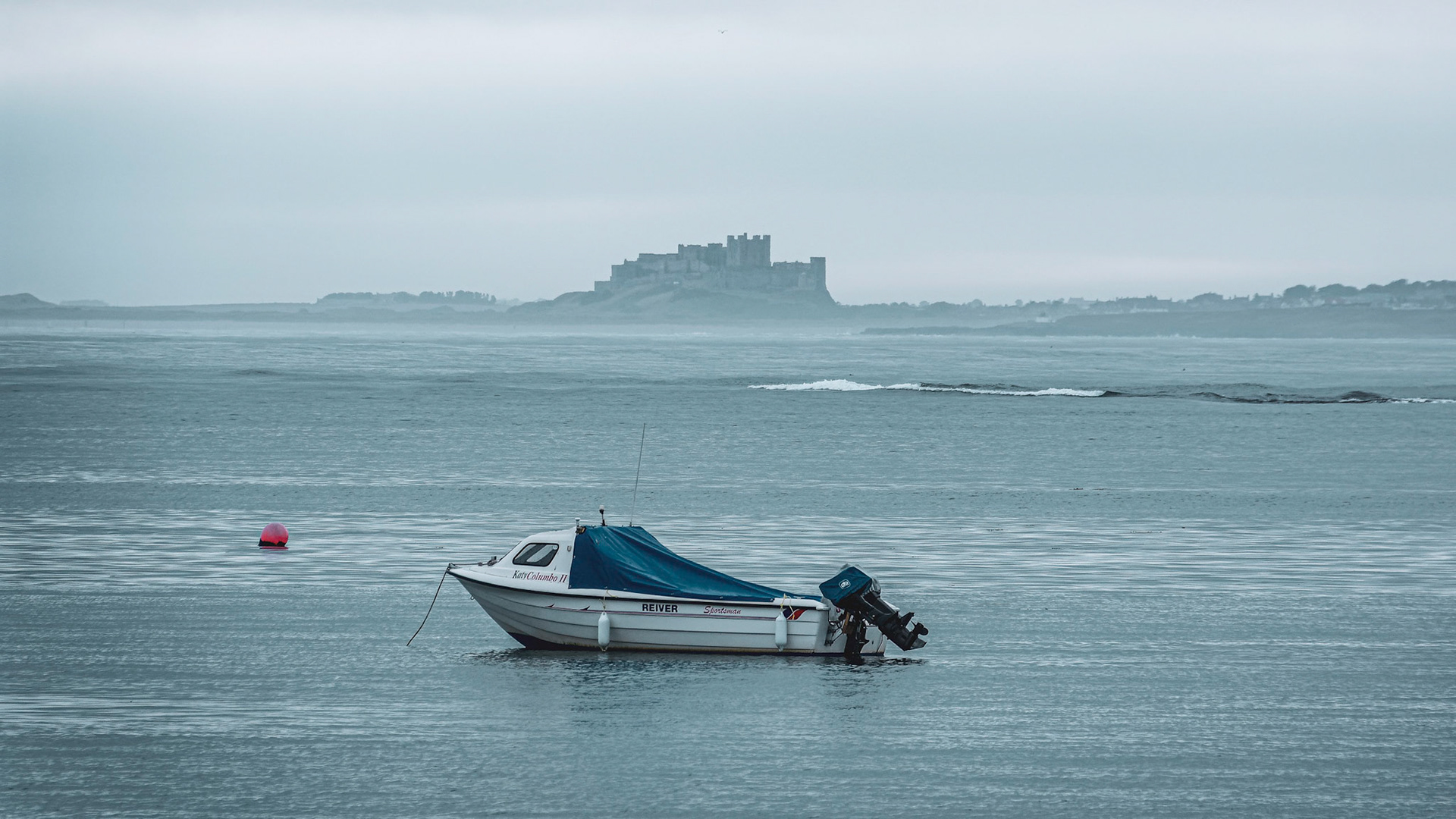 A view across the bay at Holy Island to Bamburgh Castle Northumberland.