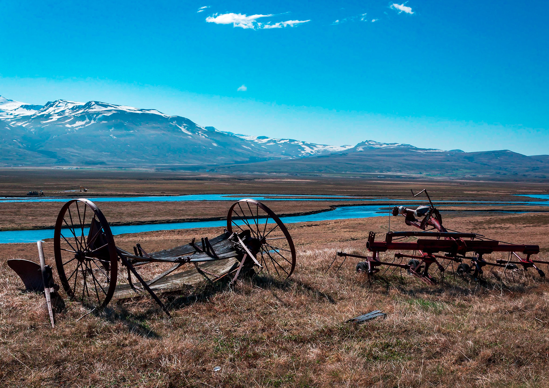 Old farm machinery stands witness over Smjörfjöll mountain range.