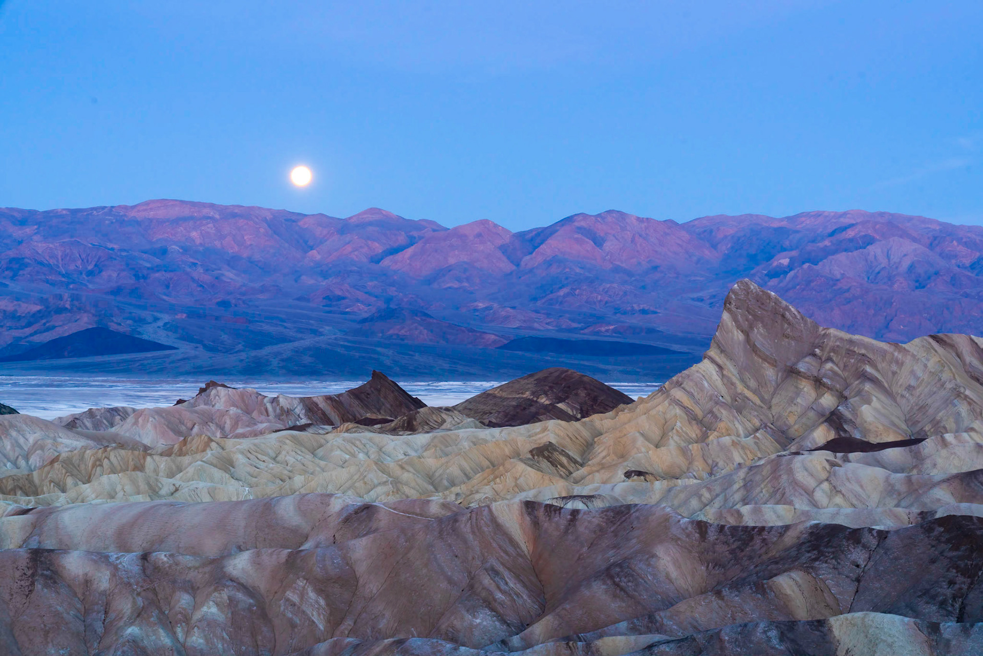 Moonset just moments after after sunrise .  Panamint Mountains in background from Zabriskie Point, Death Valley.