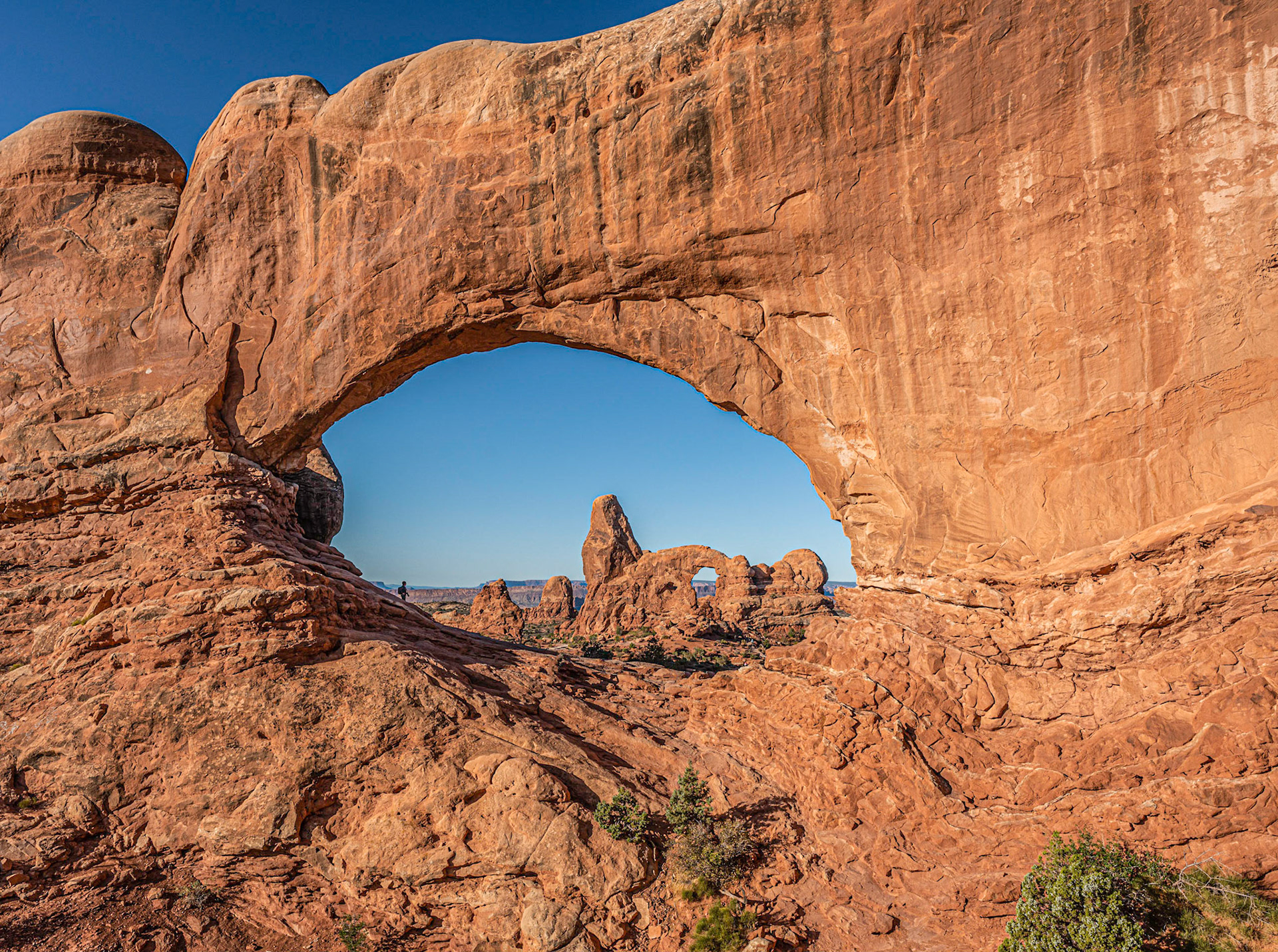 Turret Arch viewed through North Windows Arch.  For scale, Pam is in shadows on left side of North Arch.  Arches National Park.