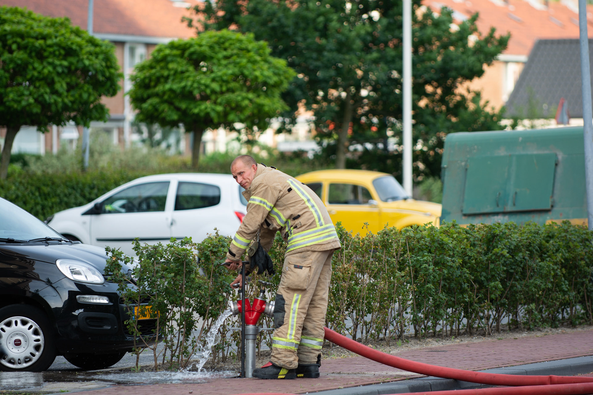 Een brandweerman van de kazerne Slotlaan draait bij een balkonbrand de waterkraan open