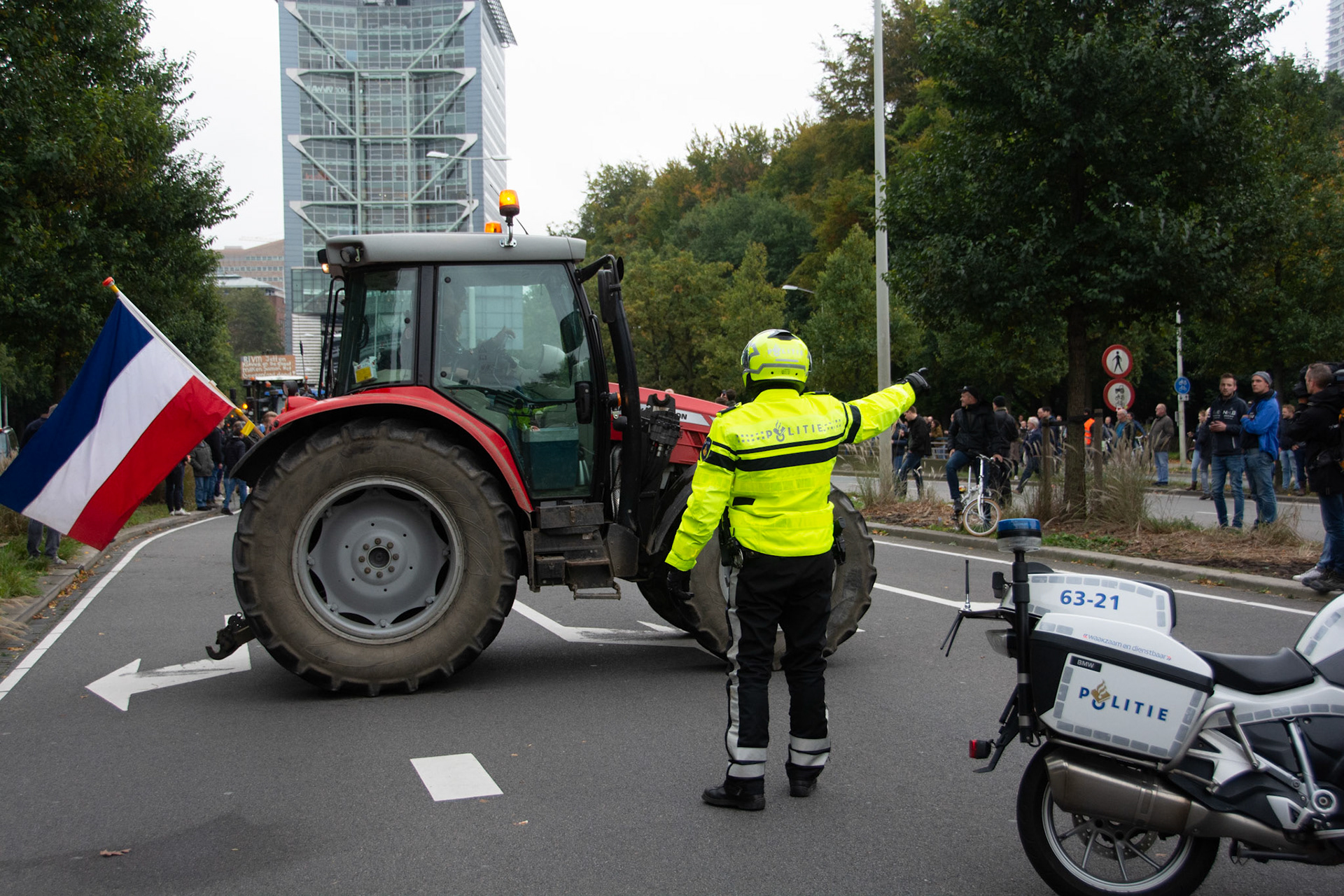 Een tractor wordt gedirigeerd door de een motoragent van de Boslaan naar de Utrechtsebaan