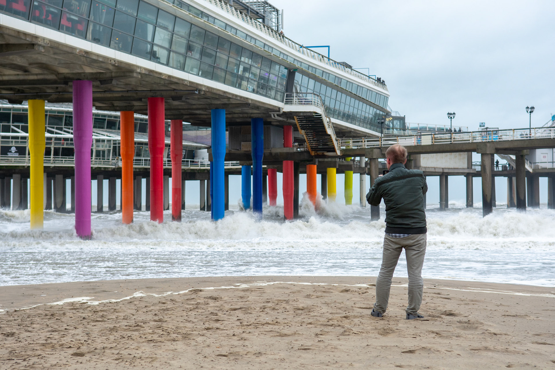 Man maakt foto van de wilde golven die tegen de pier slaan tijdens de storm Ciara