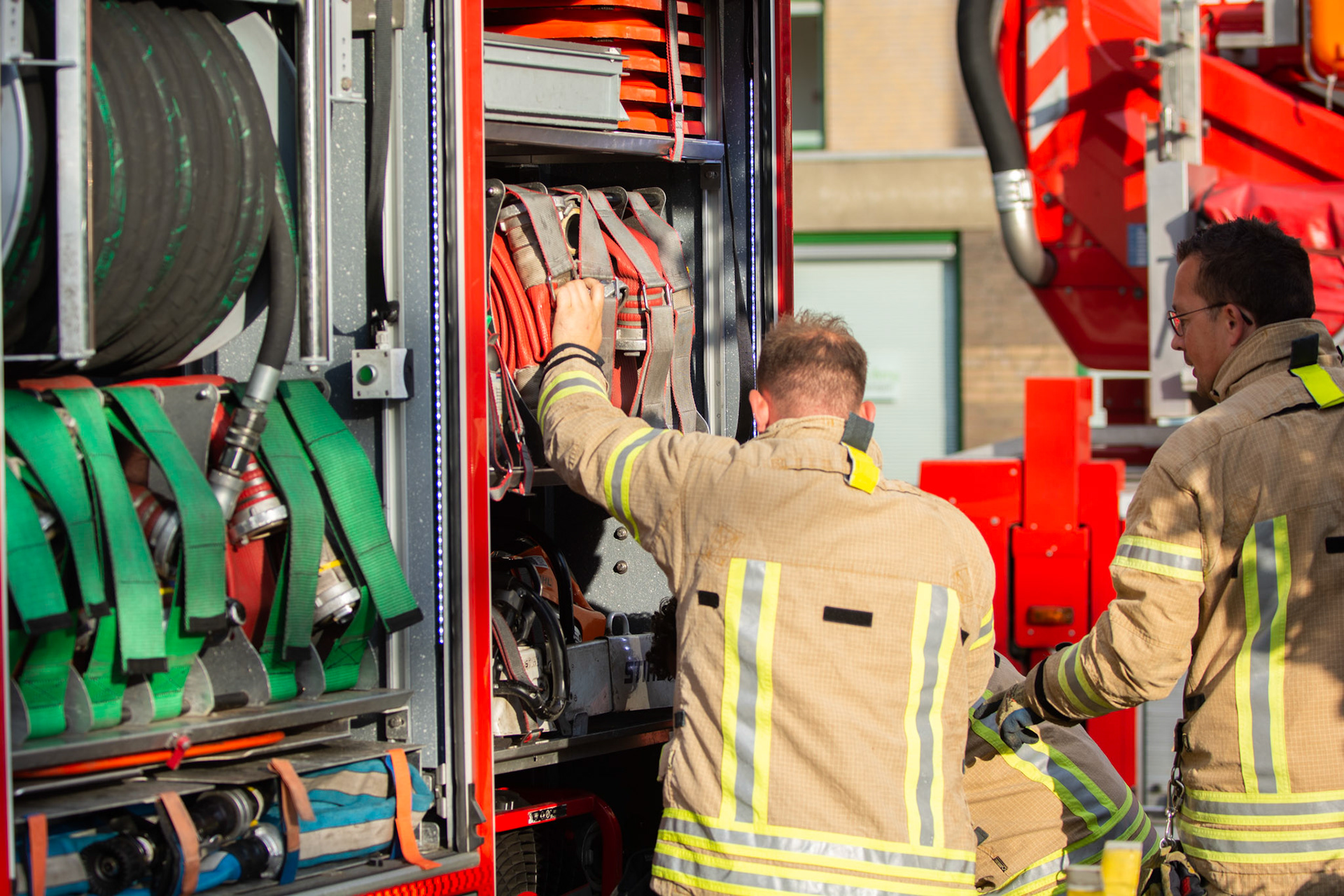 De brandslangen worden uit de brandweerauto getrokken en aangesloten