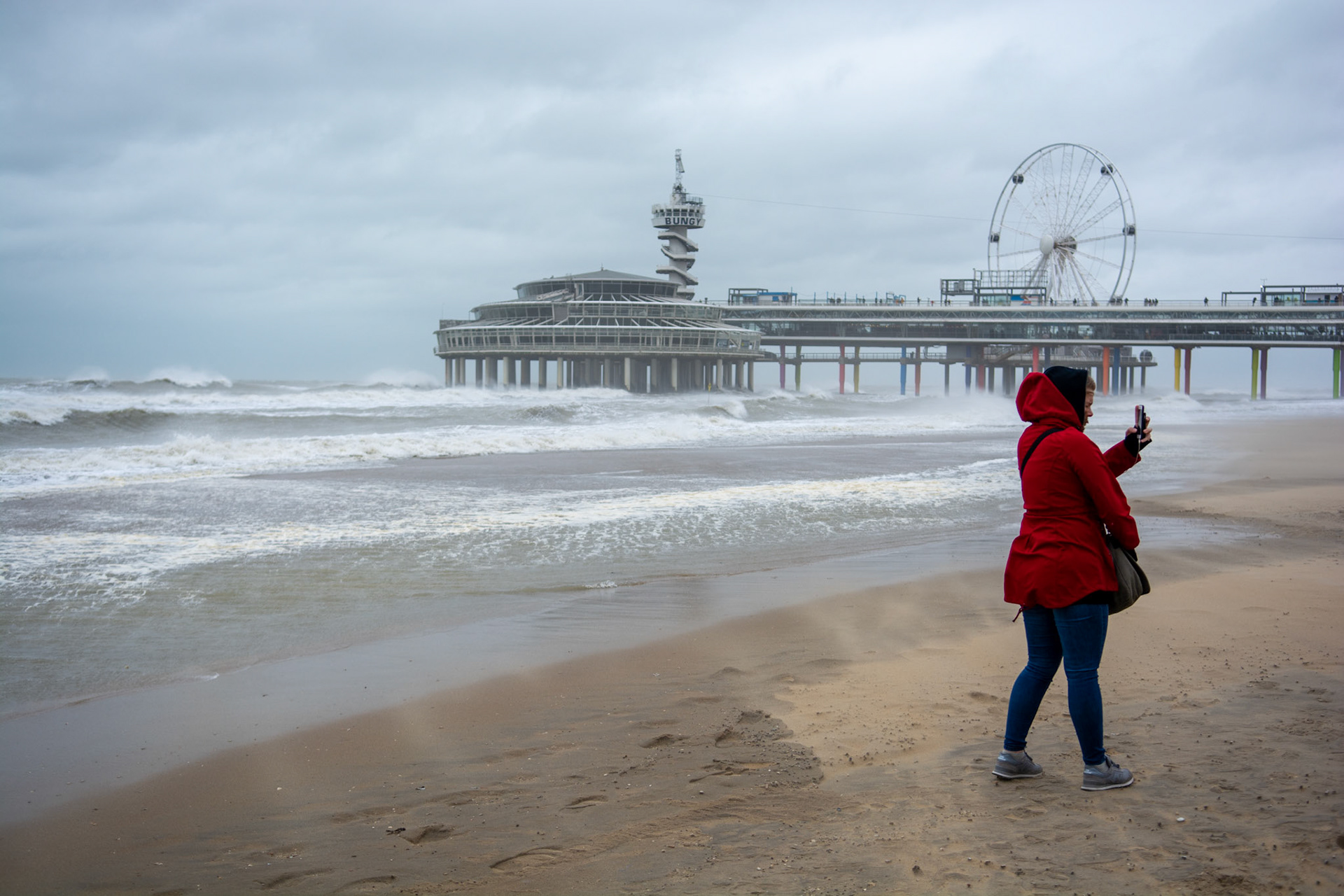 Mevrouw maakt selfie op Scheveningen strand met de woeste zee op de achtergrond