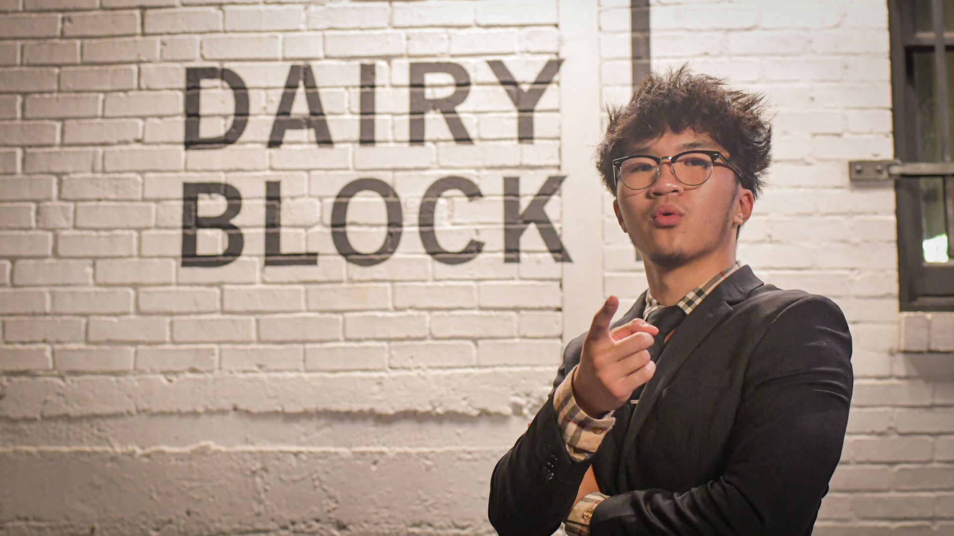 Posing for a nighttime senior portrait, Johny Vu stands in front of a sign at Milk Market in downtown Denver in the fall of 2021. Vu attended his senior year at Regis Jesuit High School in the 2021-2022 school year.
