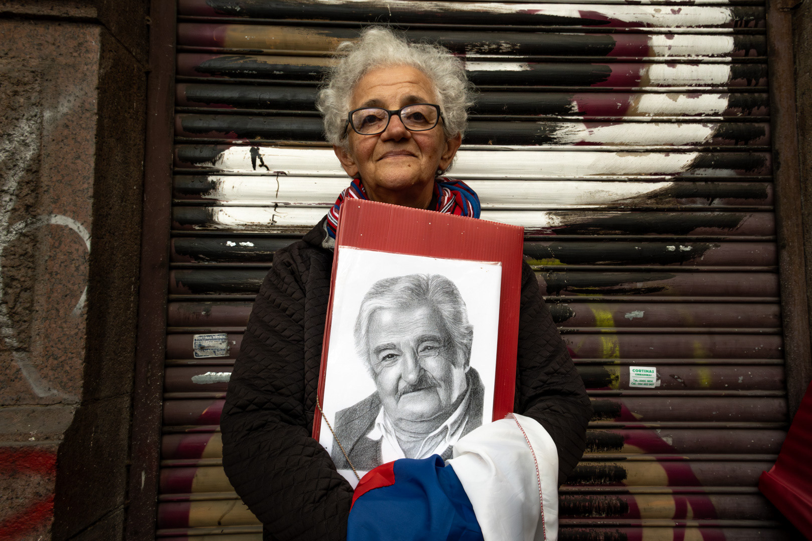 Una militante sostiene un retrato del ex presidente de la República, José Mujica, durante su cortejo fúnebre frente a la sede del Frente Amplio en Montevideo. 14 de mayo de 2025.