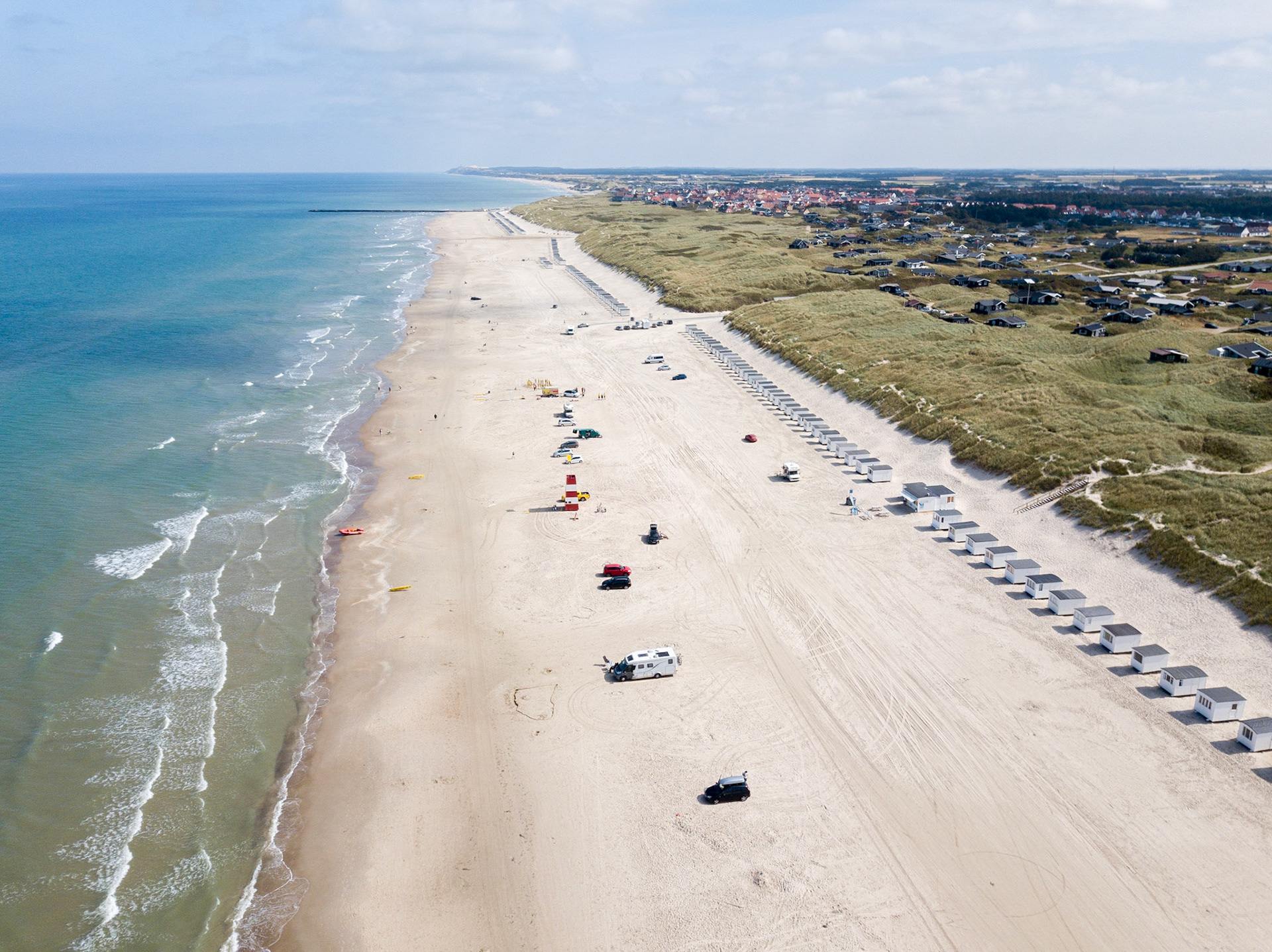 Lokken, Denmark - July 18, 2019: Aerial drone view of Lokken Beach with cars and beach huts.
