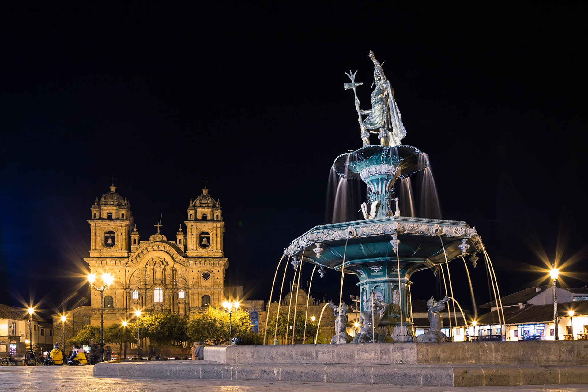 Cusco, Peru - October 06, 2015: Fountain with an Inca statue and the catholic church on the main plaza