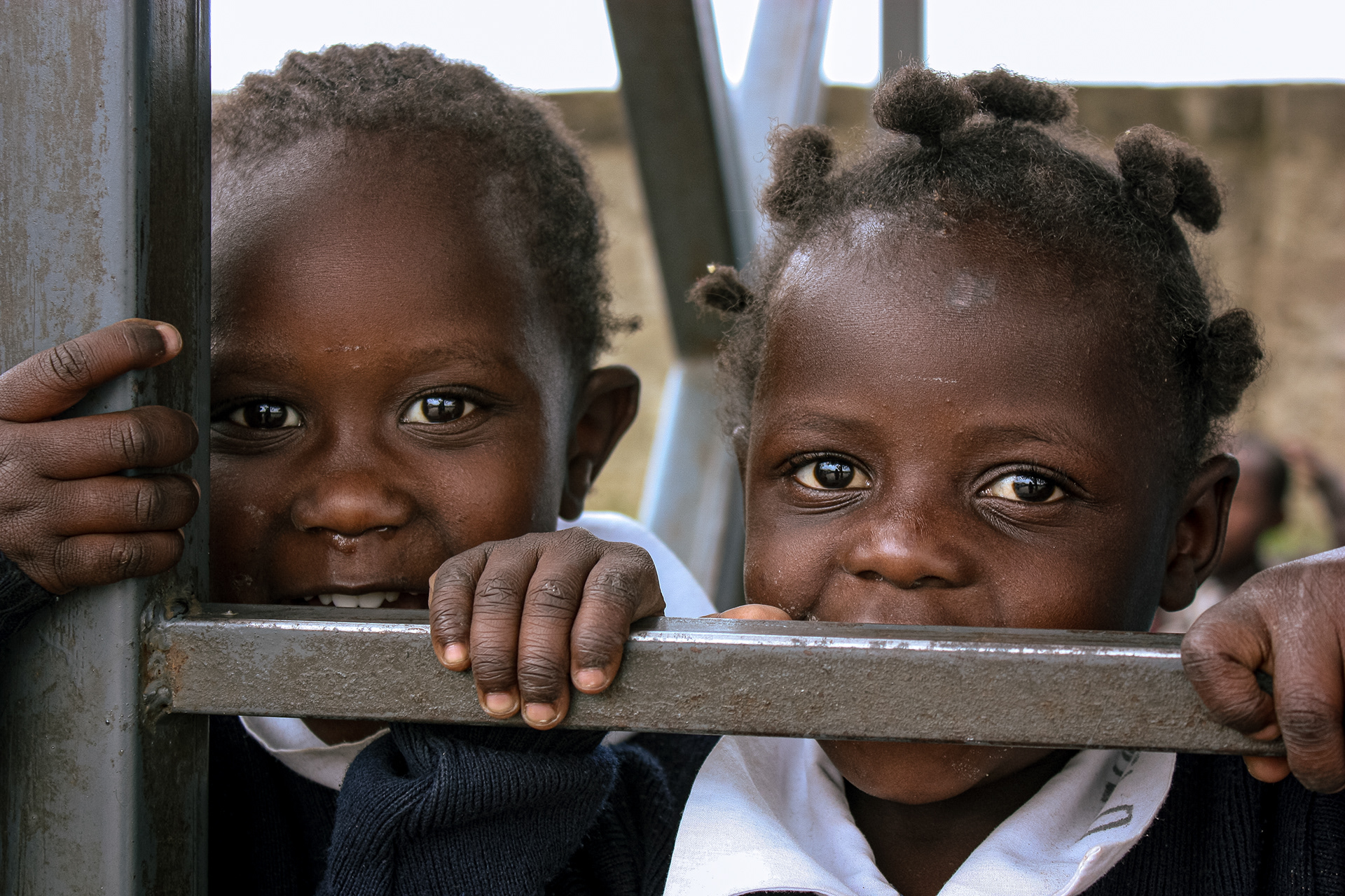 Two students peek out from a climbing frame during a break in lessons at The Walk Centre primary school in Nakuru, Kenya, on July 12, 2016.