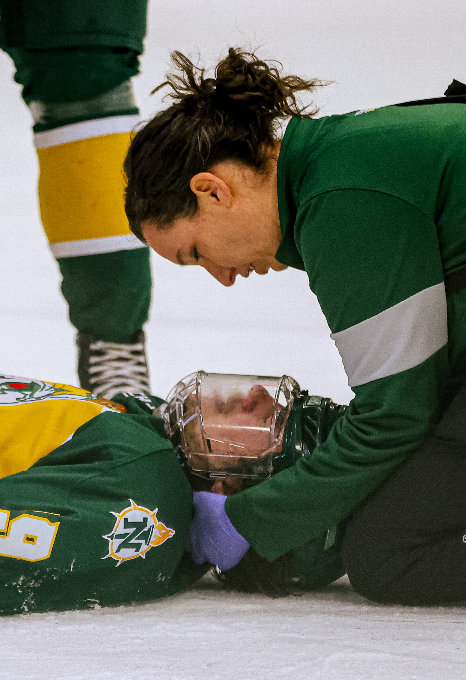 Northern Michigan’s A.J. Vanderbeck (19) is inspected by a medical official after slamming his head on the ice on Friday, February 18, 2022. For Toledo Blade.