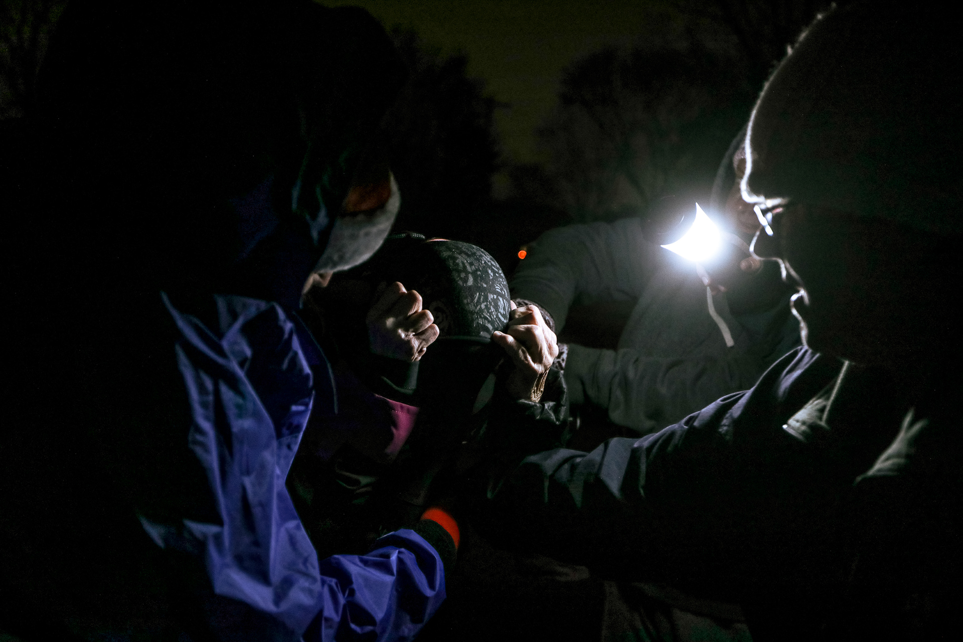 Several people help Pat Groves, center, as she attempts to put on her dry suit before the Christmas paddle at Howard Pinkley Landing in Toledo, Ohio on Sunday, December 19, 2021. For Toledo Blade.