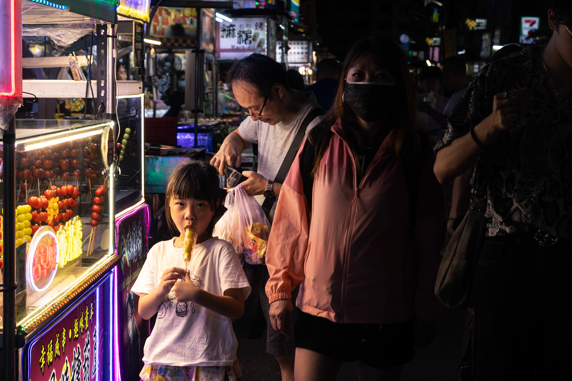 A girl eats a fruit stick at a street market in Taipei, Taiwan.