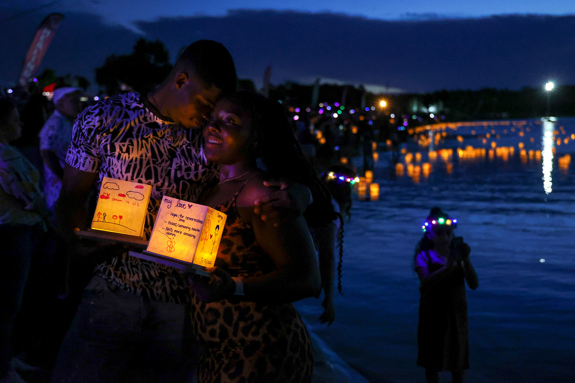 A couple stand together as they prepare to set their lantern afloat at the annual lantern lighting event in Orlando, Fla. on July 17, 2021. For Orlando Sentinel.