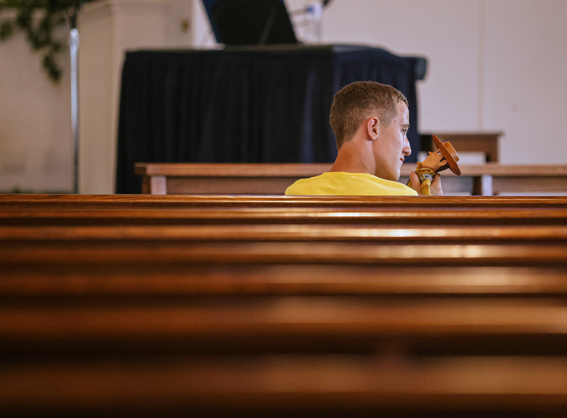 Matthew Taylor, 13, plays with his Woody doll as his father preaches at the Image Bearers service at Trinity Church of the Nazarene in Toledo on Saturday, June 25, 2022. For Toledo Blade.