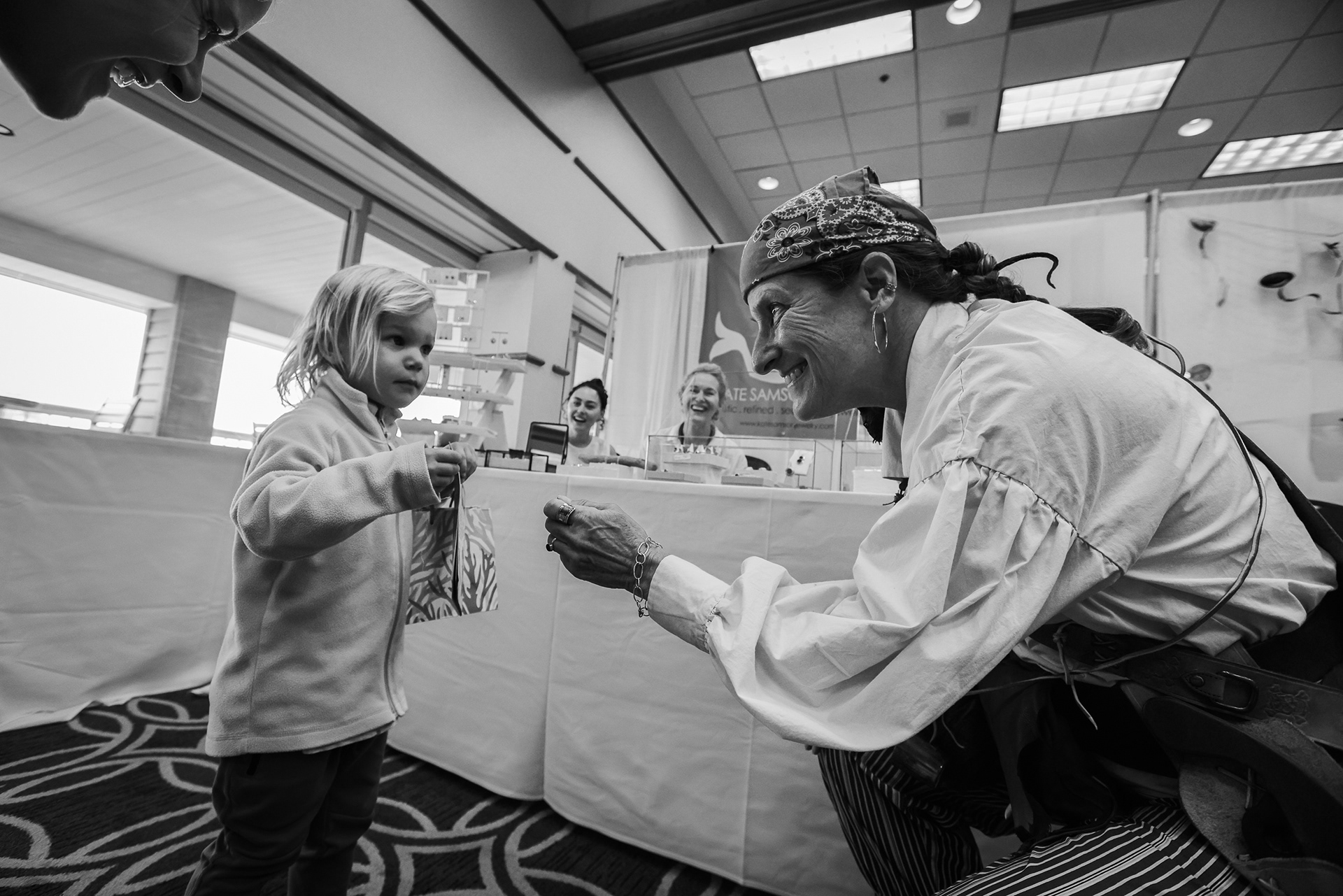Lisa Gordon, right, of Marooned Crab Creations, gives Andi Gilpin, 2, a piece of pirate treasure at the 16th annual North American Sea Glass Festival at the Maumee Bay Lodge in Oregon, Ohio on Sunday, May 22, 2022. For Toledo Blade.