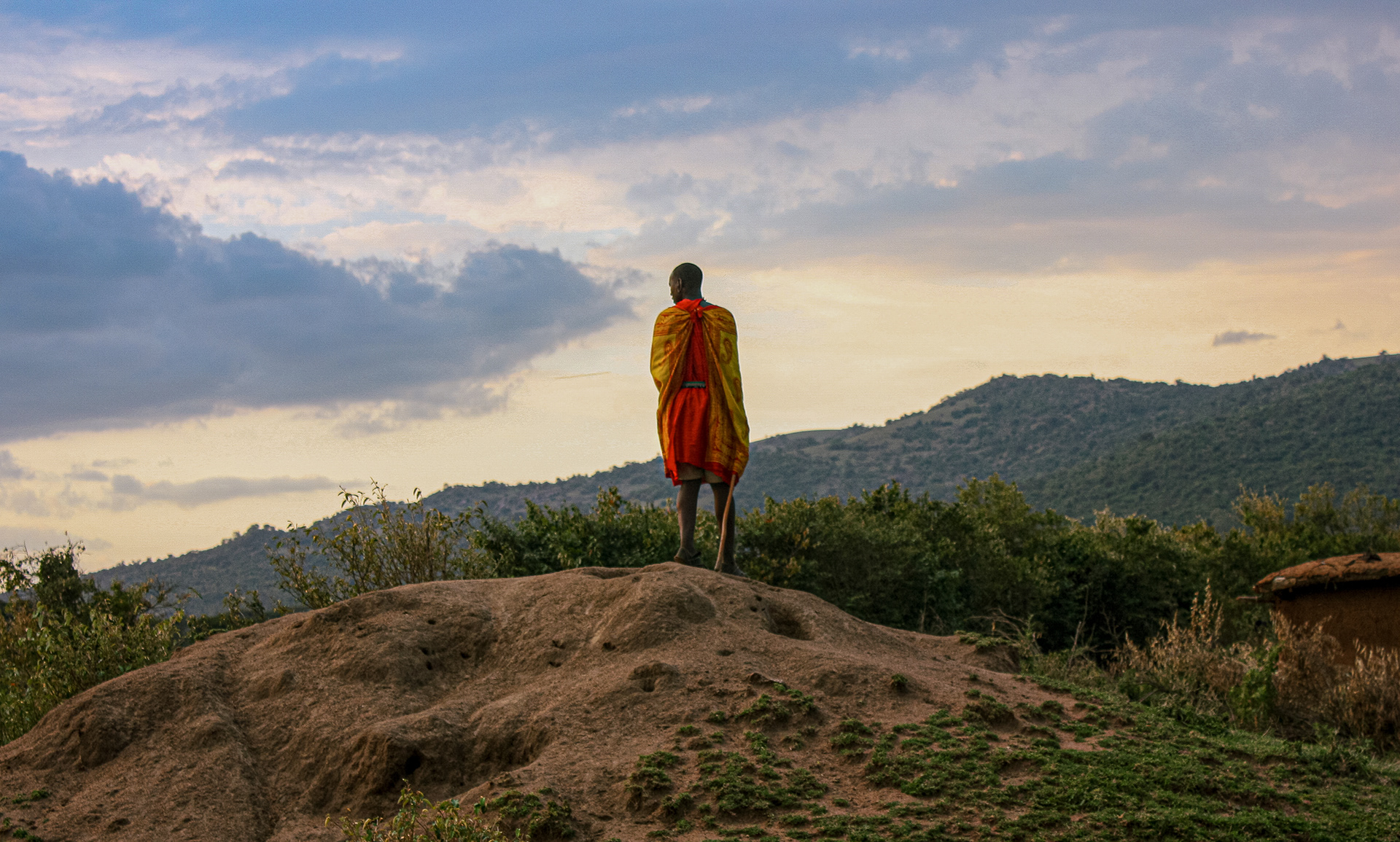 A member of the Maasai tribe stands on top of a dirt mound looking for predators in Maasai Mara, Kenya on July 1, 2016. 