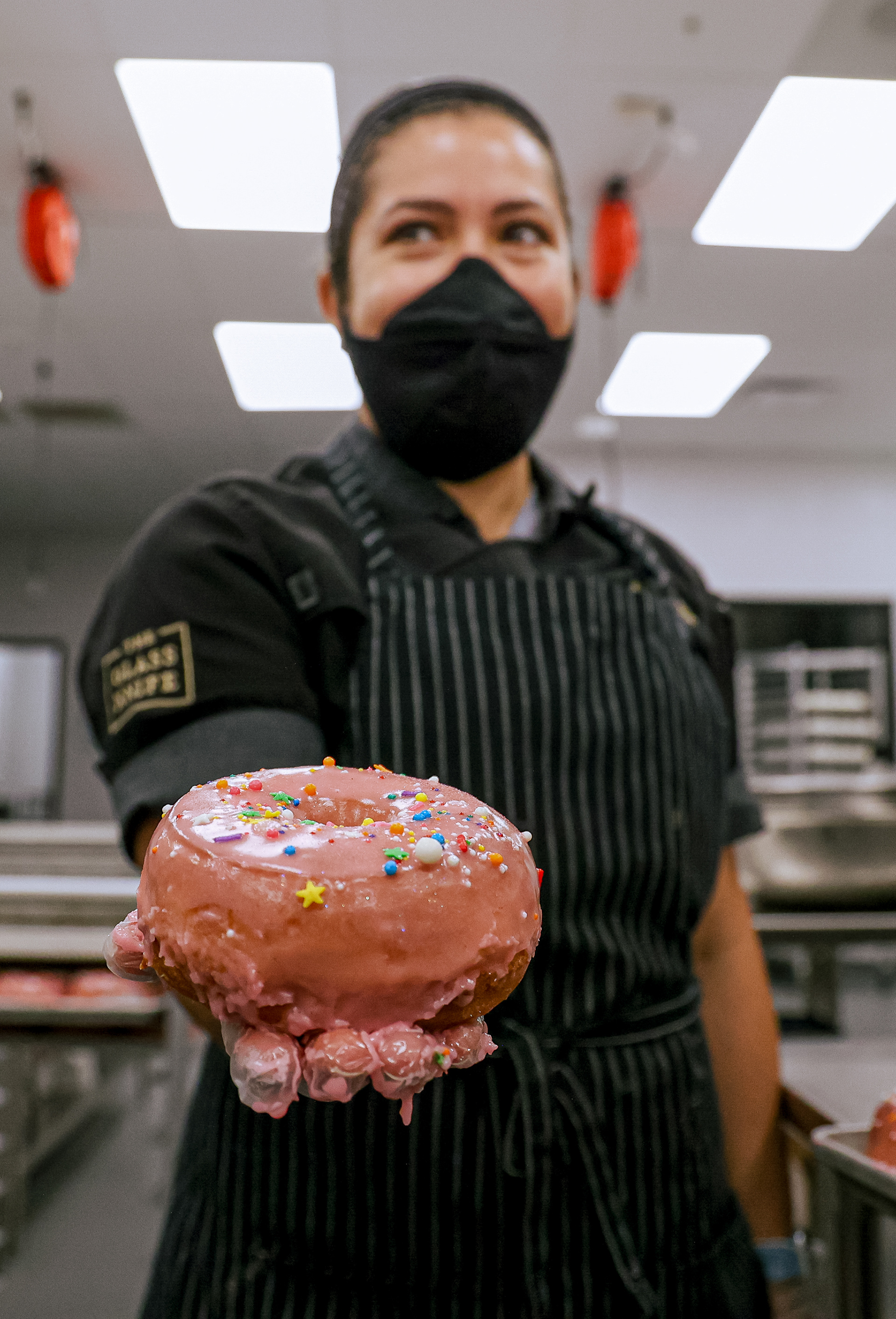 Aileen Camarena, sous chef at The Glass Knife, holds up a finished pink donut in her kitchen in downtown Orlando on Monday, May 31, 2021. The donut would later be transported to the store’s location several blocks away, where the donuts made in the kitchen are served fresh each morning. For Orlando Sentinel.