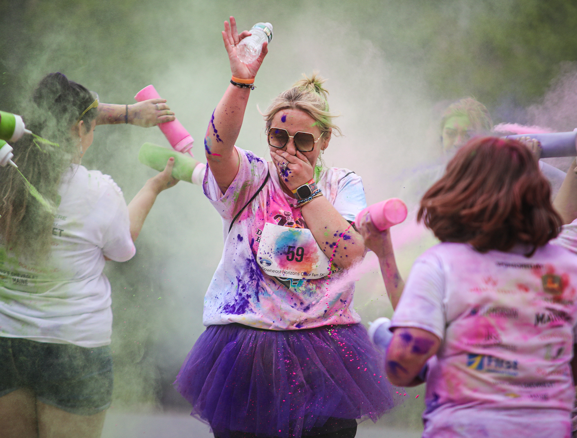 A runner holds her nose as she runs through the color blast at the finish line at the Downeast Horizons Color Fun 5K in Ellsworth on Saturday, May 20, 2023. For Ellsworth American.