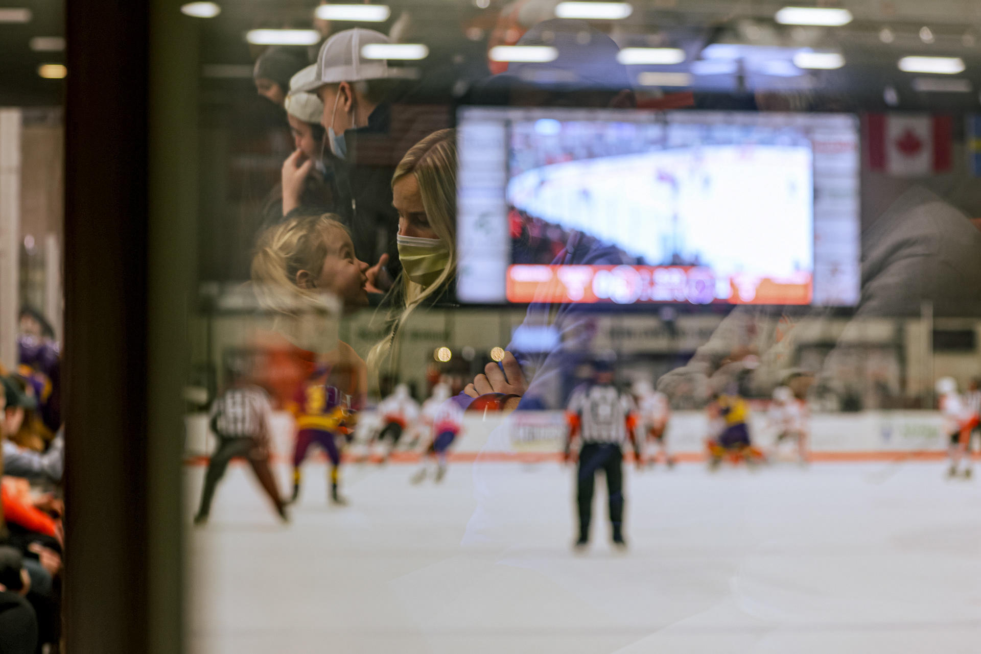 A mother and daughter seen in a reflection smile at each other during a BGSU hockey game on February 4, 2022. For Toledo Blade.