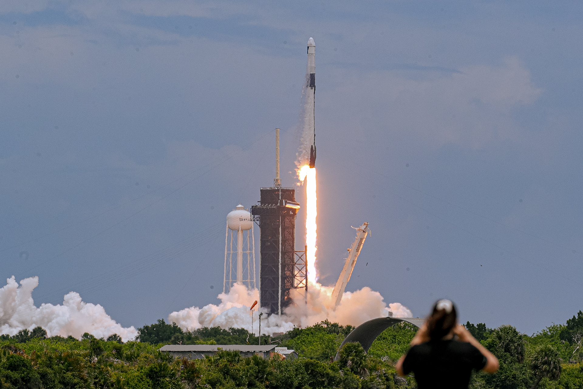 A woman holds her phone up to film the launch of SpaceX CRS-22, an unmanned supply mission set for the International Space Center, from the Kennedy Space Center in Cape Canaveral, Fla. on Thursday, June 3, 2021. For Orlando Sentinel.