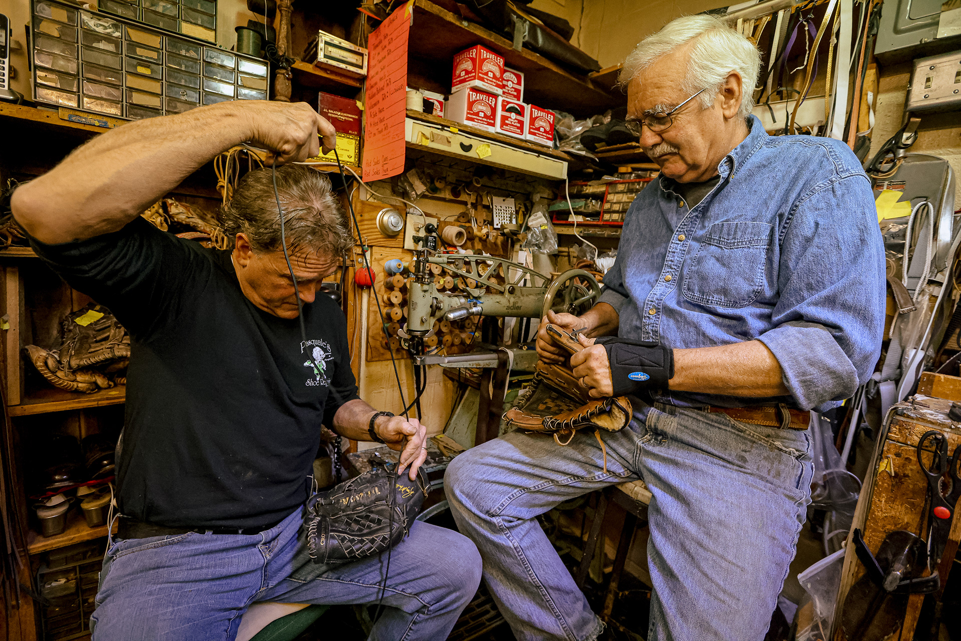 Dino DiTerlizzi, left, and brother Mario DiTerlizzi, co-owners of Pasquale and Son's Shoe Repair in Toledo, Ohio, work on stitching two damaged baseball gloves on Wednesday, May 4, 2022. For Toledo Blade