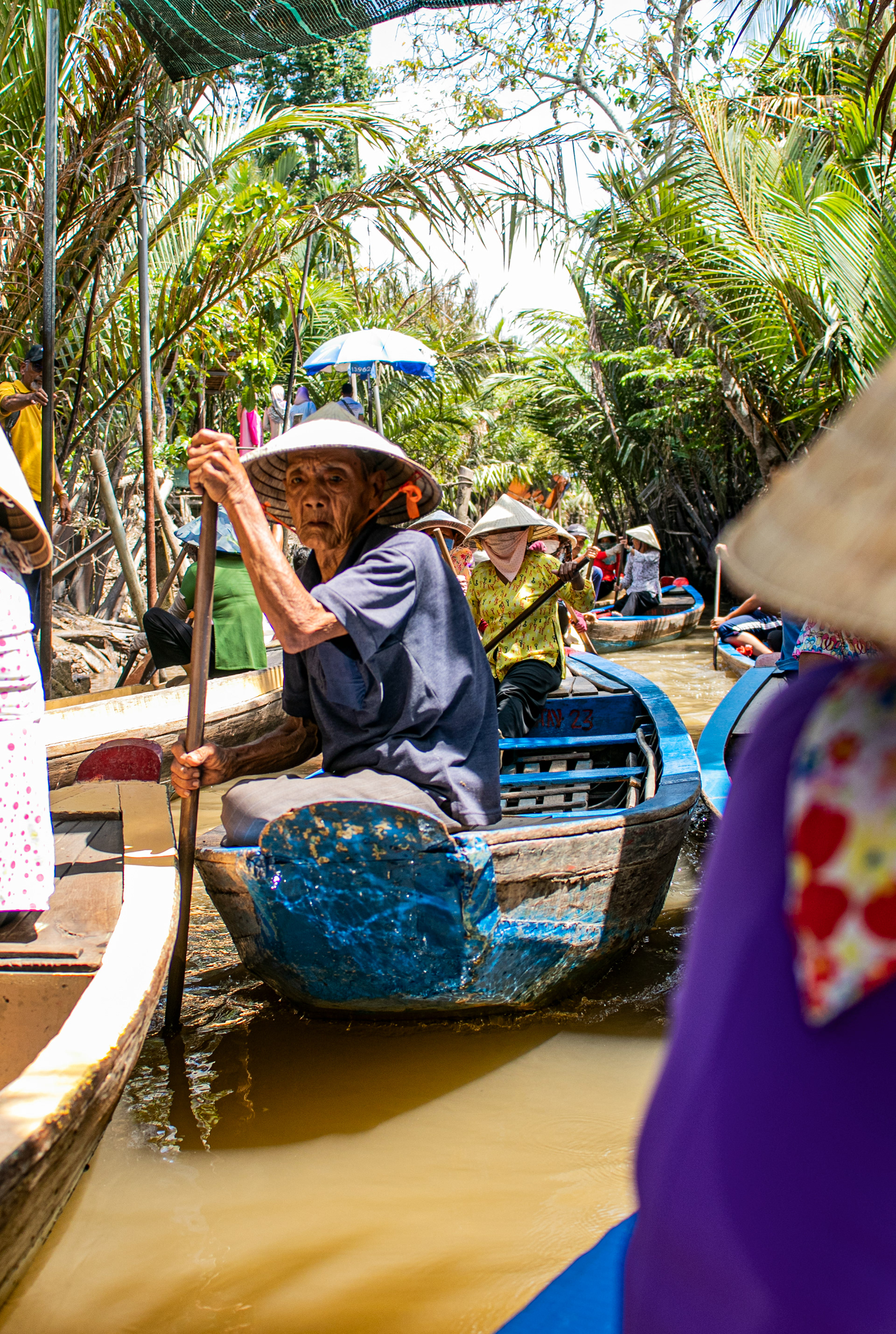 An elderly man rows a boat through a river passage near Hoi An, Vietnam.