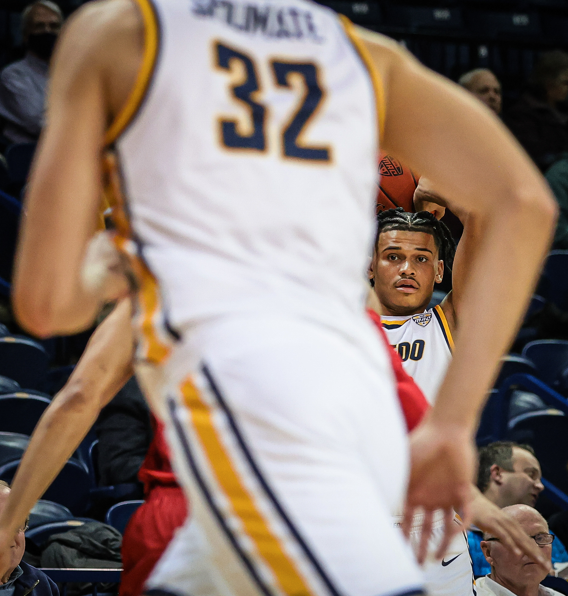 University of Toledo's Ryan Rollins prepares to throw the ball to a teammate, as seen through the arms of another player. 