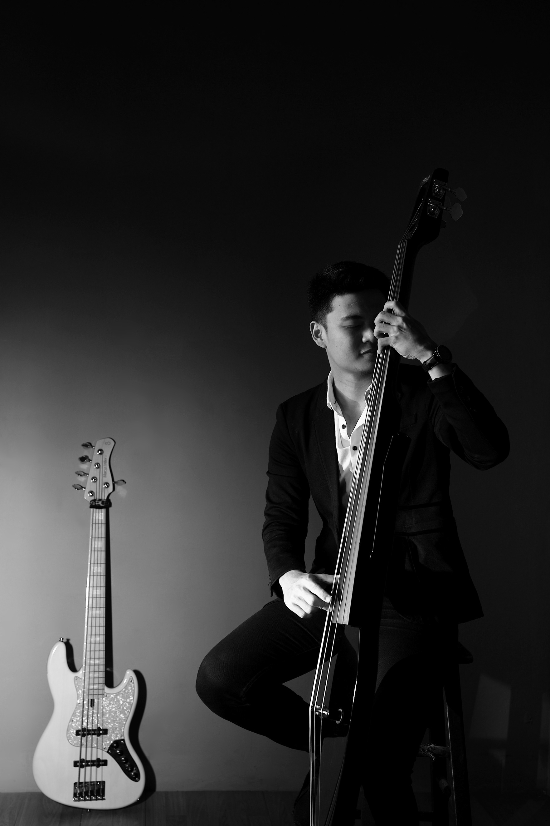 photograph of a mann playing bass wearing a black suit and white shirt