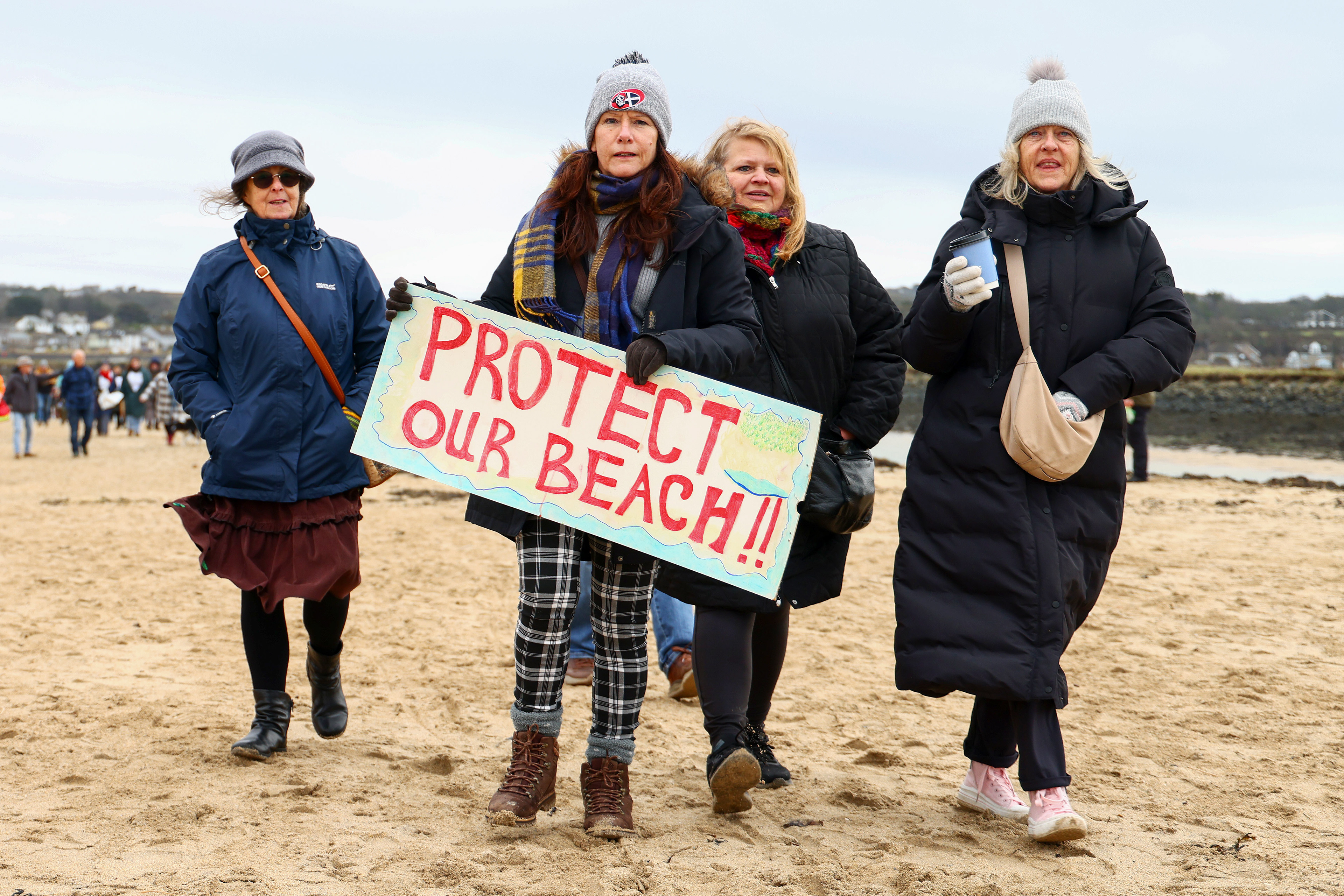Demonstrators gather during an SOS Cornwall protest that is trying to prevent the selling off of sand from Hayle Beach in Cornwall, England. There has been outrage and concerns recently that sand is being 'stolen' from the beach. Hayle Towans Beach was voted the United Kingdom’s best beach in 2024. Shot for Stella Pictures LTD
