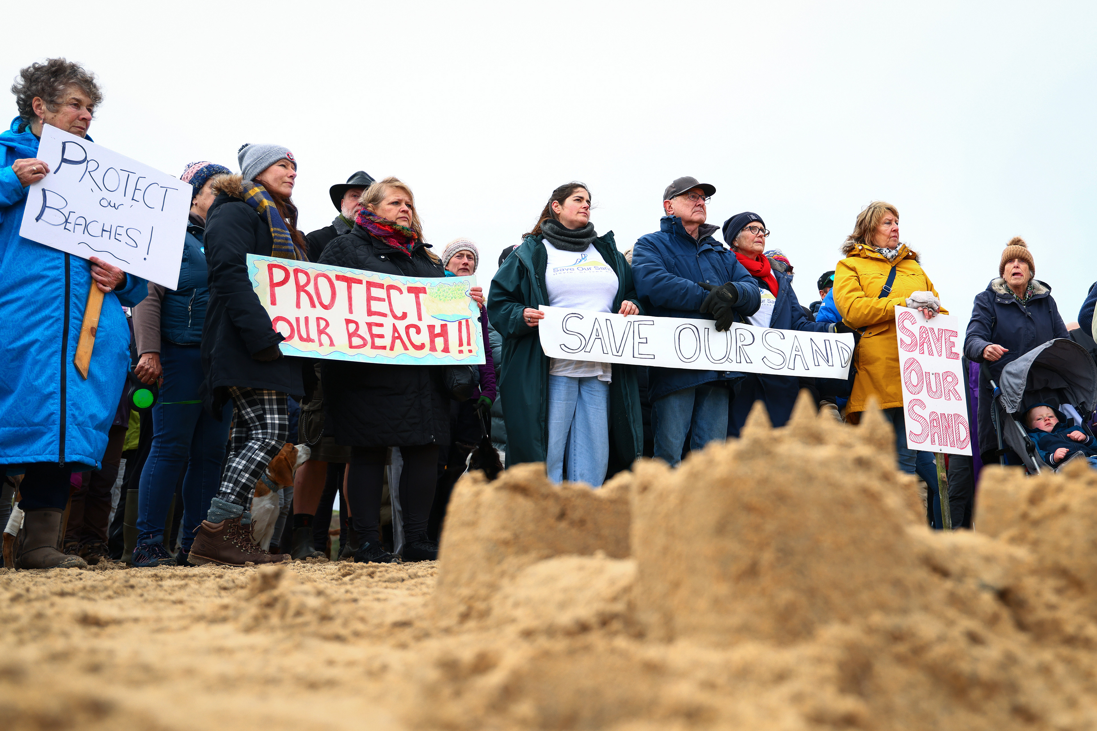 Demonstrators gather during an SOS Cornwall protest that is trying to prevent the selling off of sand from Hayle Beach in Cornwall, England. There has been outrage and concerns recently that sand is being 'stolen' from the beach. Hayle Towans Beach was voted the United Kingdom’s best beach in 2024. Shot for Stella Pictures LTD