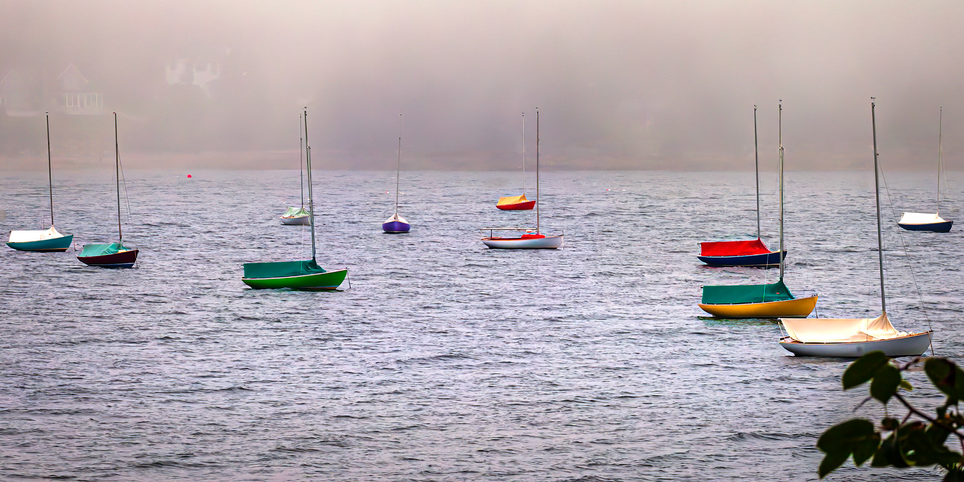 Sail boats sitting at anchor on rainy day