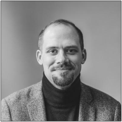 Grayscale headshot of a man wearing a dark turtleneck sweater and blazer.