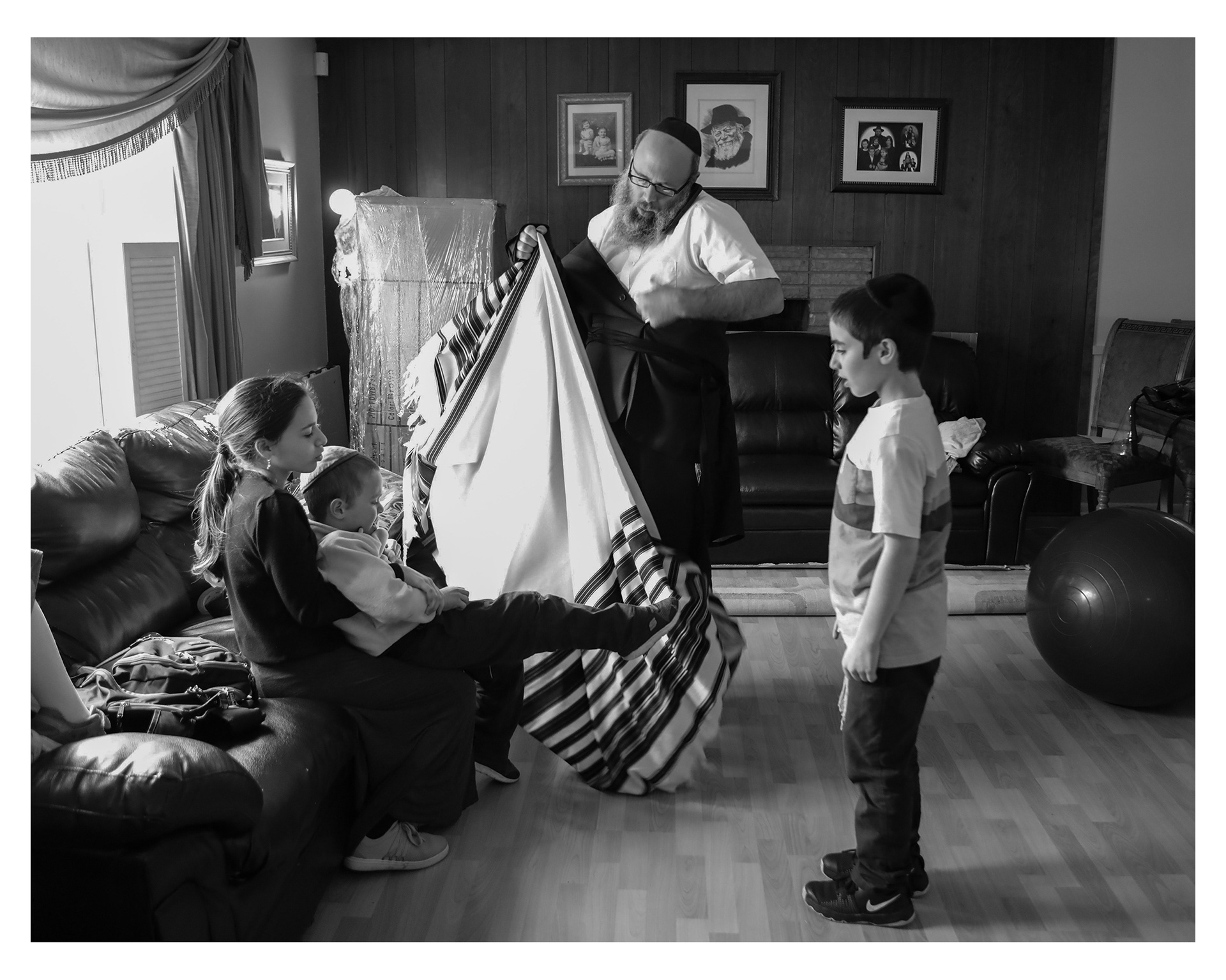 From left to right, Chani, 12, holds her youngest brother Levi, 4, while their dad Rabbi Hendel Weingarten and other brother Gavi, 8, tend to Levi's scraped knee at their home in East Lansing, Wednesday, April 17, 2019.