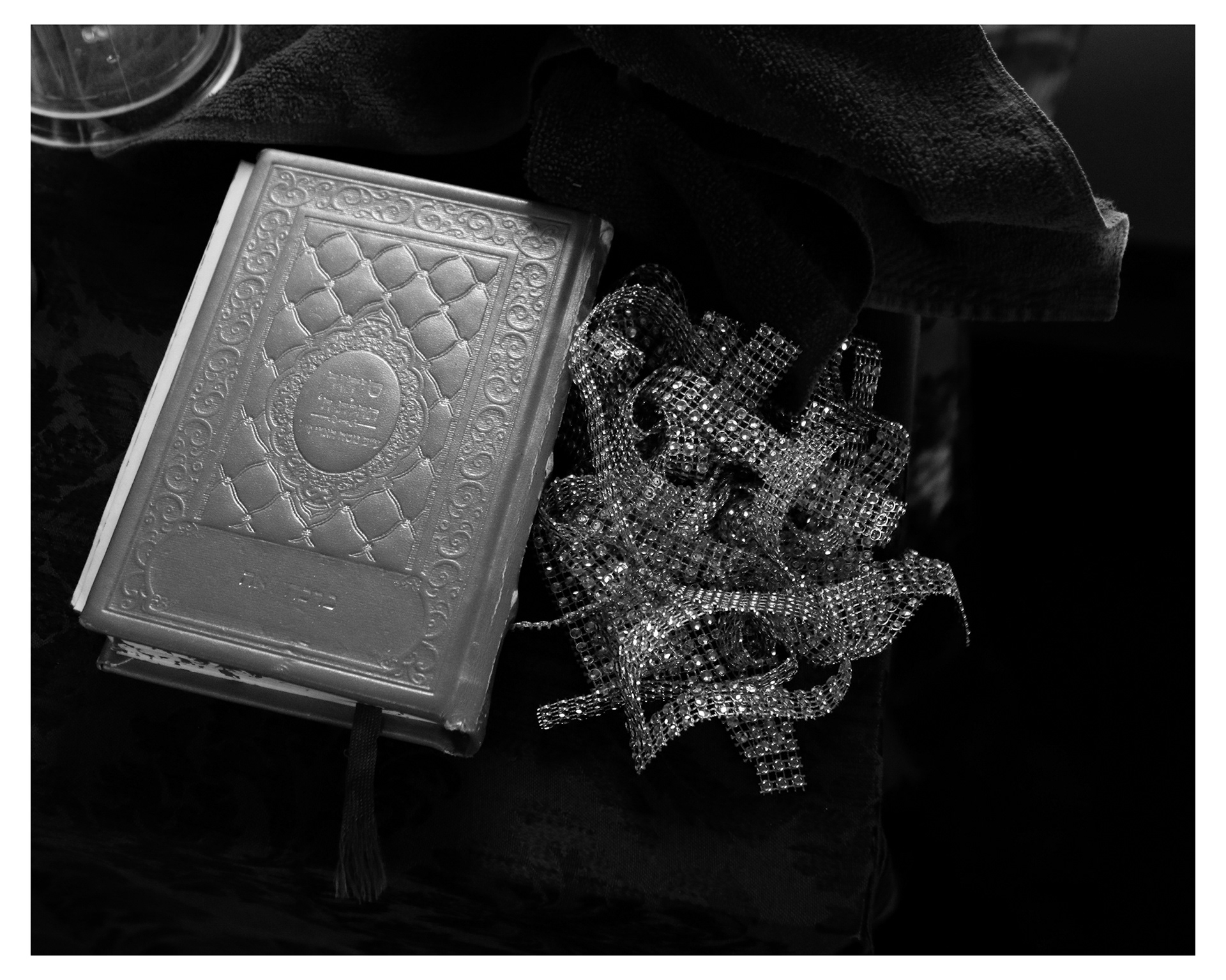 A siddur, or prayer book, sits on a table next to ribbon being used to decorate for Tu BiShvat, the Israeli Festival of Trees.  