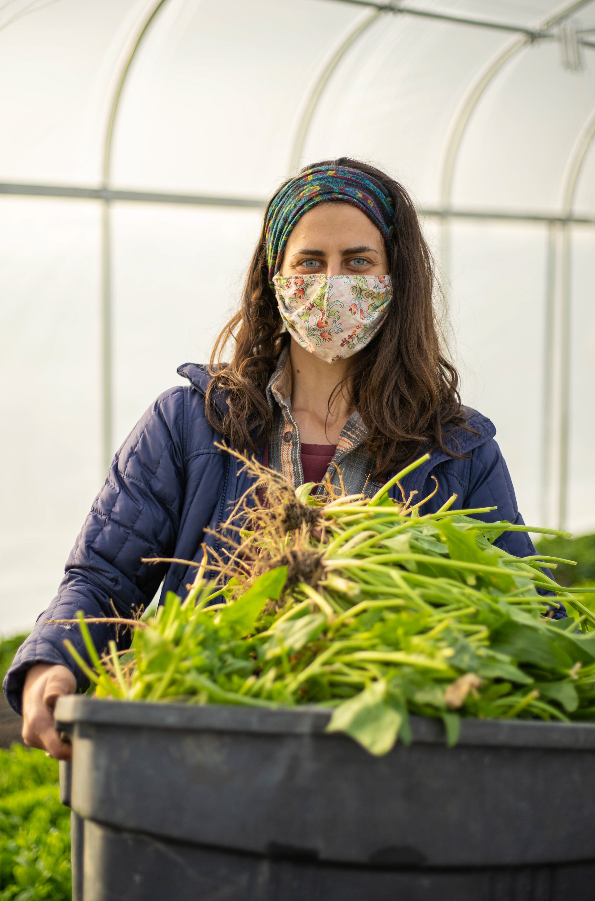 Laurie Kensler, harvest manager at Green Wagon Farm, poses for a photo with a bin of spinach for compost.