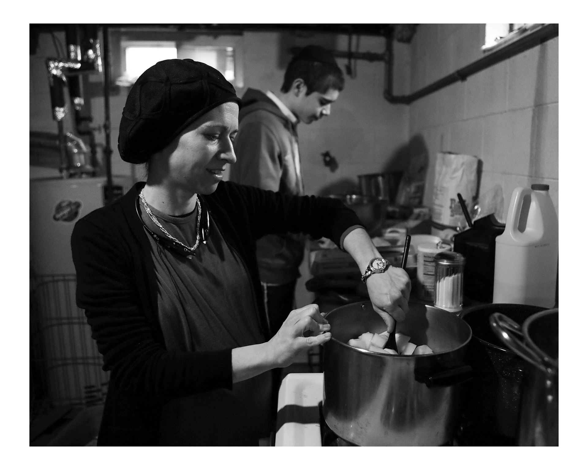 Bracha Leah Weingarten stirs a version of a Jewish stew called cholent in preparation for Passover. Her oldest son Avremel who is home from Arkansas, helps peel potatoes.